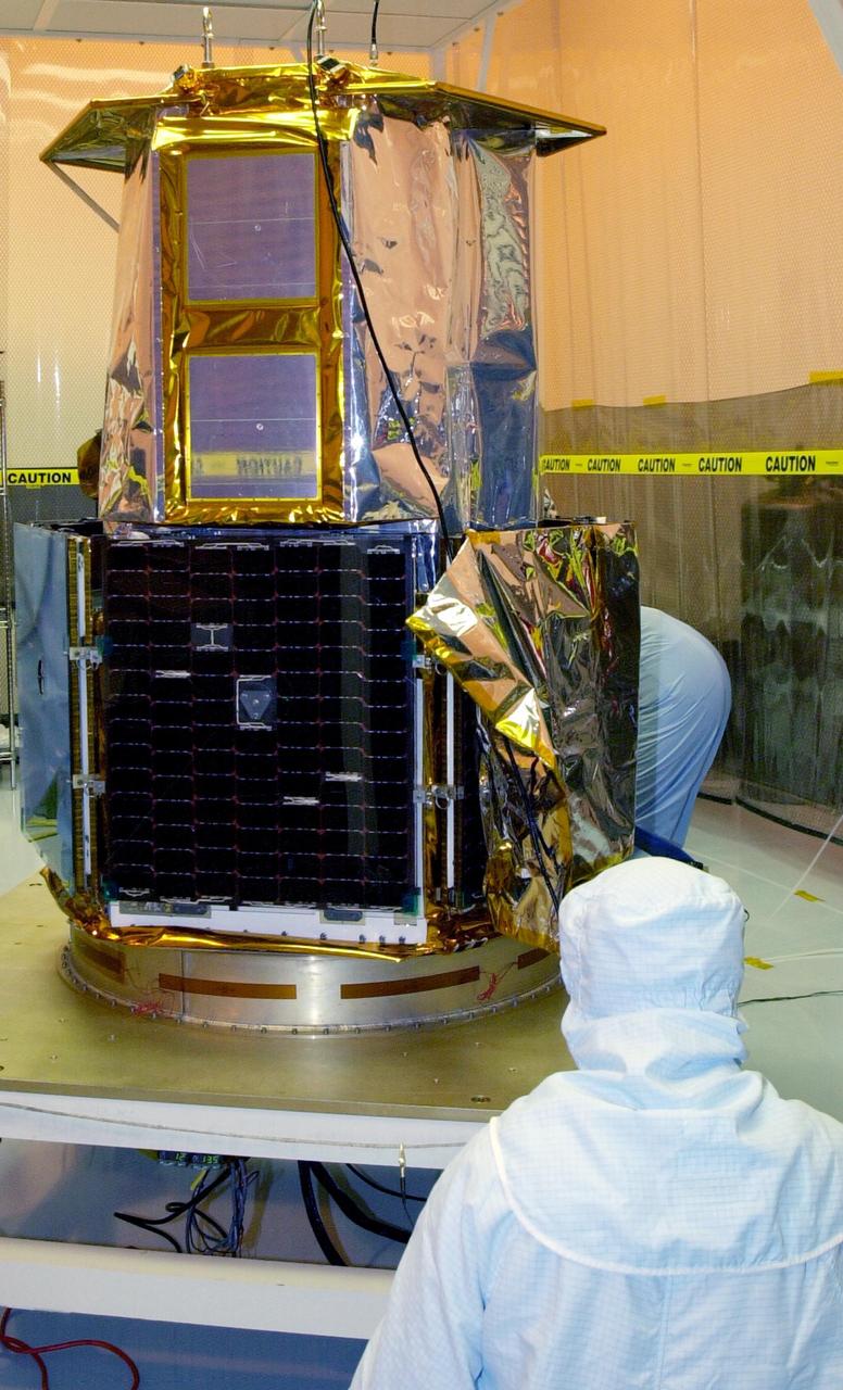 KENNEDY SPACE CENTER, FLA. - Workers in the Multi-Purpose Processing Facility return to the SORCE satellite after solar array testing is complete. SORCE is equipped with four instruments that will measure variations in solar radiation much more accurately than anything now in use and observe some of the spectral properties of solar radiation for the first time. With data from NASA’s SORCE mission, researchers should be able to follow how the Sun affects our climate now and in the future. The SORCE project is managed by NASA’s Goddard Space Flight Center. The instruments on the SORCE spacecraft are built by the Laboratory for Atmospheric and Space Physics (LASP). Launch of SORCE aboard a Pegasus XL rocket is scheduled for mid-December 2002. Launch site is Cape Canaveral Air Force Station, Fla.