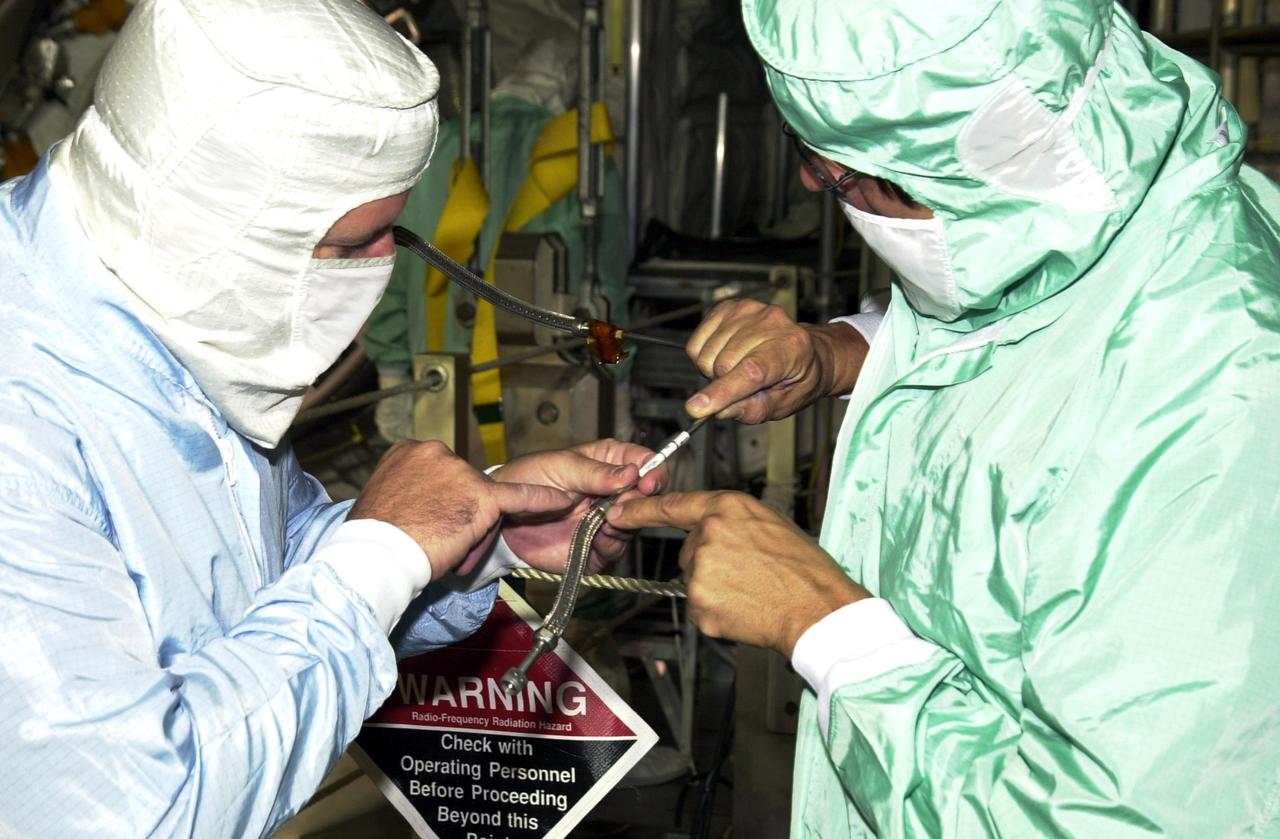 KENNEDY SPACE CENTER, FLA. -- Workers on Launch Pad 39A inspect an oxygen flex hose fitting.  Through manual inspection and using helium detectors, the flex hose was identified as the source of an oxygen leak in Endeavour's mid-body. Visual inspection found a deformity in the flex line braid where it connects to rigid tubing. The entire flex hose assembly and bulkhead fitting were removed early today, and work is under way to complete the installation of a replacement. 