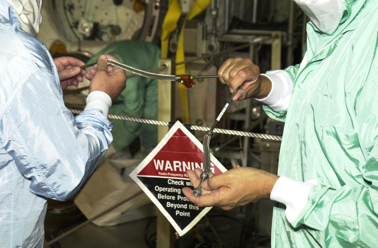 KENNEDY SPACE CENTER, FLA. --  Workers on Launch Pad 39A inspect an oxygen flex hose fitting.  Through manual inspection and using helium detectors, the flex hose was identified as the source of an oxygen leak in Endeavour's mid-body. Visual inspection found a deformity in the flex line braid where it connects to rigid tubing. The entire flex hose assembly and bulkhead fitting were removed early today, and work is under way to complete the installation of a replacement. 