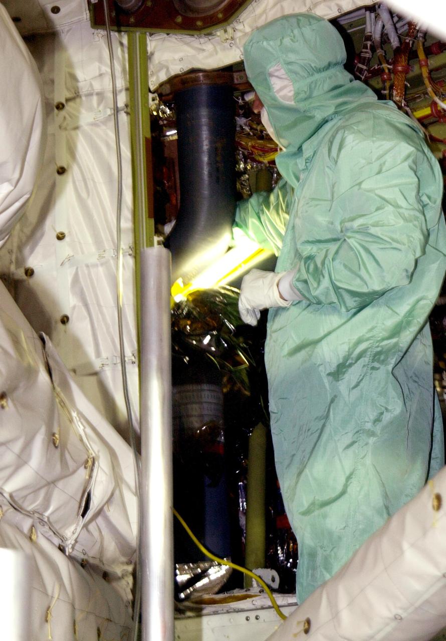 KENNEDY SPACE CENTER, FLA. -- Workers on Launch Pad 39A remove Endeavour's oxygen flex hose from the mid-body to inspect it for the source of an oxygen leak. Visual inspection found a deformity in the flex line braid where it connects to rigid tubing. Manual inspection and helium detectors identified the flex hose as the source of the oxygen leak. Work is under way to complete the installation of a replacement.