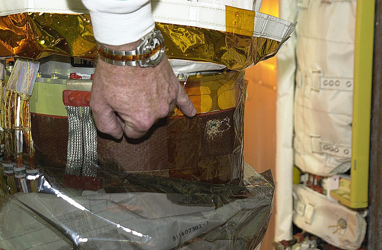 KENNEDY SPACE CENTER, FLA. --  The site being identified in the photo is the scrape on the surface of the honeycomb shell on Endeavour's robotic arm.  The scrape occurred while work platforms were being installed to gain access to repair the oxygen leak in the Shuttle's mid-body.   The site will be cut out and ultrasound testing  will be done on the structure underneath.  Launch of Endeavour on mission STS-113 has been postponed until no earlier than Nov. 22.  
