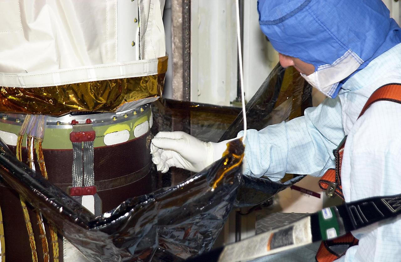 KENNEDY SPACE CENTER, FLA. -- One of a team of robotic experts looks at the site of the scrape on the surface of the the robotic arm's honeycomb shell.  The scrape occurred while work platforms were being installed to gain access to repair the oxygen leak in Endeavour's mid-body.   The site will be cut out and ultrasound testing  will be done on the structure underneath. Launch of Endeavour on mission STS-113 has been postponed until no earlier than Nov. 22.      