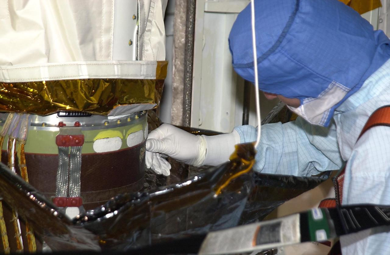 KENNEDY SPACE CENTER, FLA. -- One of a team of robotic experts looks at the site of the scrape on the surface of the honeycomb shell on the robotic arm that occurred while work platforms were being installed to gain access to repair the oxygen leak in the Shuttle's mid-body.   The site will be cut out and ultrasound testing  will be done on the structure underneath. Launch of Endeavour on mission STS-113 has been postponed until no earlier than Nov. 22.    