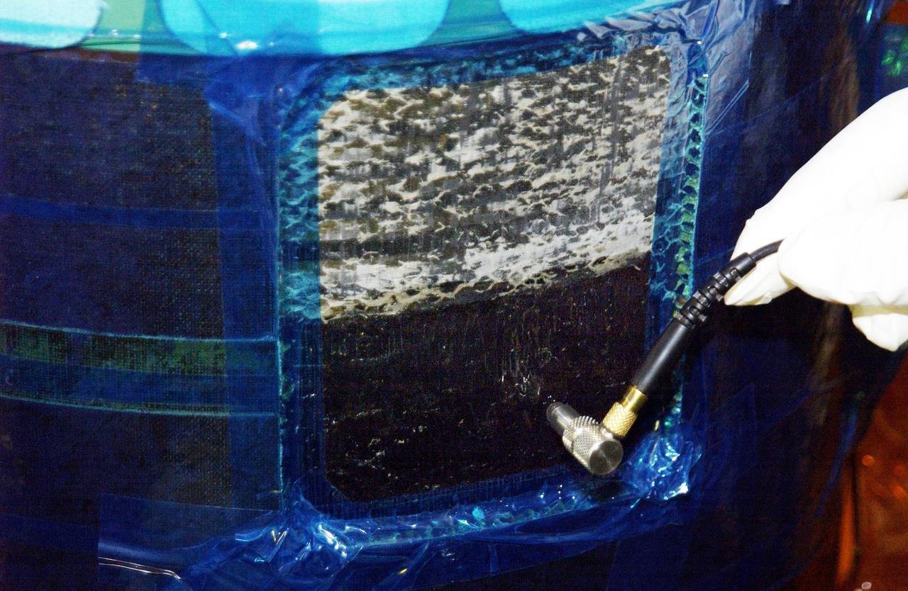 KENNEDY SPACE CENTER, FLA. --  An ultrasound device is held at the site where the honeycomb shell around Endeavour's robotic arm has been cut to inspect the arm. A scrape of the shell occurred while work platforms were being installed to gain access to repair the oxygen leak in the Shuttle's mid-body.  Launch of Endeavour on mission STS-113 has been postponed until no earlier than Nov. 22.    