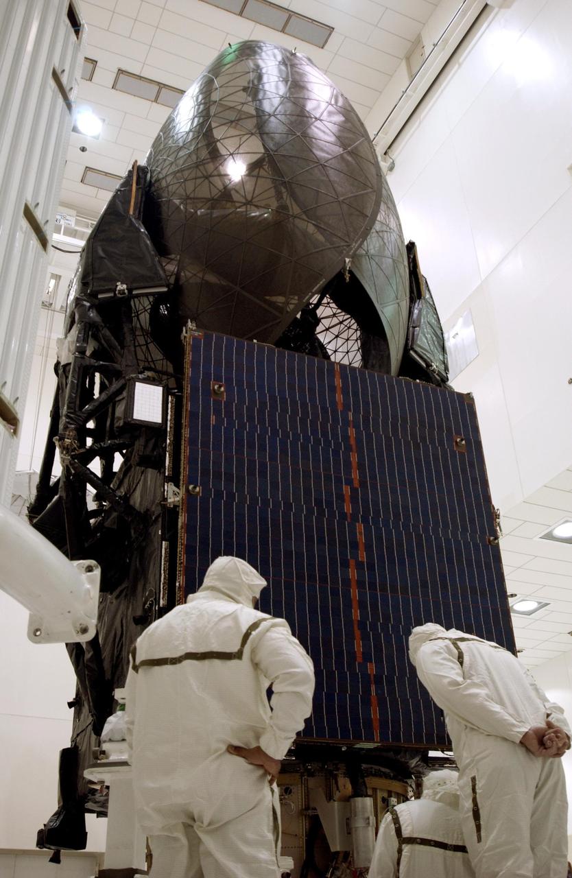 KENNEDY SPACE CENTER, FLA. -- Workers keep check on  the TDRS-J satellite (foreground) as the fairing (background) moves toward it for encapsulation.  The satellite is scheduled to be launched aboard a Lockheed Martin Atlas IIA-Centaur rocket from Launch Complex 36-A, Cape Canaveral Air Force Station, Fla., on Dec. 4.  The third in a series of telemetry satellites, TDRS-J will help replenish the current constellation of geosynchronous TDRS satellites. The TDRS System is the primary source of space-to-ground voice, data and telemetry for the Space Shuttle. It also provides communications with the International Space Station and scientific spacecraft in low-Earth orbit such as the Hubble Space Telescope. This new advanced series of satellites will extend the availability of TDRS communications services until about 2017. 