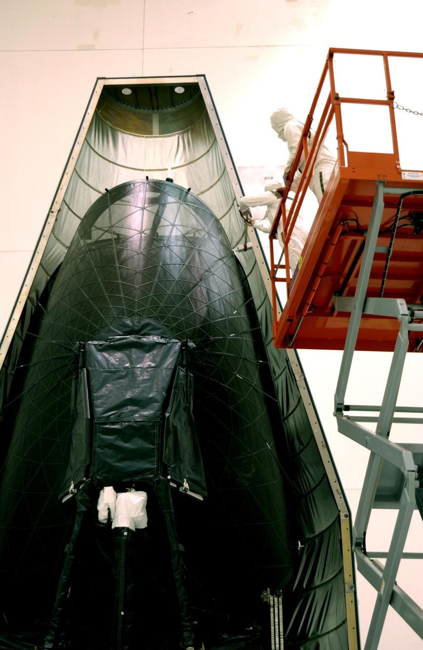 KENNEDY SPACE CENTER, FLA. -- The TDRS-J satellite  rests inside the first half of the fairing during encapsulation. The satellite is scheduled to be launched aboard a Lockheed Martin Atlas IIA-Centaur rocket from Launch Complex 36-A, Cape Canaveral Air Force Station, Fla., on Dec. 4.  The third in a series of telemetry satellites, TDRS-J will help replenish the current constellation of geosynchronous TDRS satellites. The TDRS System is the primary source of space-to-ground voice, data and telemetry for the Space Shuttle. It also provides communications with the International Space Station and scientific spacecraft in low-Earth orbit such as the Hubble Space Telescope. This new advanced series of satellites will extend the availability of TDRS communications services until about 2017.
