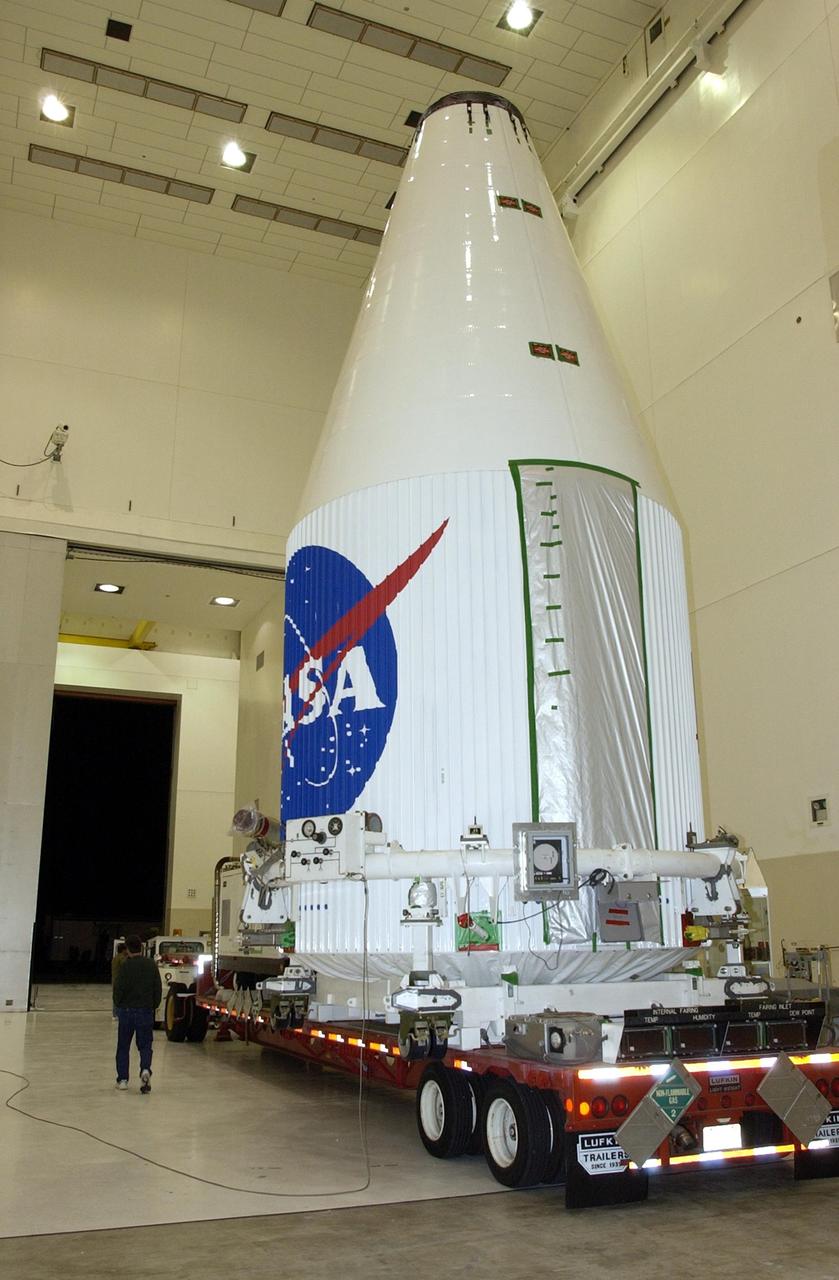 KENNEDY SPACE CENTER, FLA. - A transporter carrying the encapsulated TDRS-J satellite makes its way to the exit.  The satellite is being taken to Launch Complex 36-A, Cape Canaveral Air Force Station, for a launch aboard an Atlas IIA vehicle Dec. 4.  The launch window is 9:42 to 10:22 p.m. EST. TDRS-J, the third in a series of telemetry satellites, will help replenish the current constellation of geosynchronous TDRS satellites that are the primary source of space-to-ground voice, data and telemetry for the Space Shuttle. The satellites also provide communications with the International Space Station and scientific spacecraft in low-Earth orbit such as the Hubble Space Telescope. This new advanced series of satellites will extend the availability of TDRS communications services until about 2017.