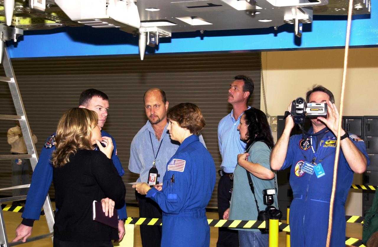 KENNEDY SPACE CENTER, FLA. - At the SPACEHAB facility in Cape Canaveral, STS-114 crew members, dressed in blue flight suits -- Pilot James Kelly (left), Commander Eileen Collins (center) and Mission Specialist Stephen Robinson (holding videocamera) -- participate in familiarization activities on the module that will fly on the STS-114 mission with support personnel looking on. STS-114 is a utilization and logistics flight that will carry Multi-Purpose Logistics Module Raffaello and the External Stowage Platform (ESP-2), as well as the Expedition 7 crew, to the International Space Station. Launch of STS-114 is currently targeted for March 1, 2003.