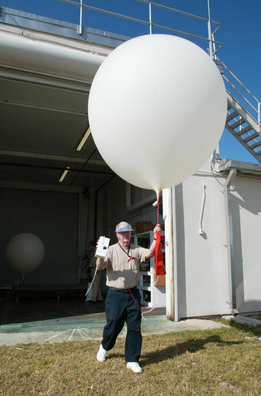 KENNEDY SPACE CENTER, FLA. - Stephen Ezell, meteorological systems operator at Weather Station A, Cape Canaveral Air Force Station, walks out with a weather balloon that he will release. Such balloons are released twice a day. The package in Ezell's hand is a radio sonde that collects temperature and humidity data as the balloon rises. The data is released to agencies nationwide, including the 45th Space Wing which uses the data for its daily weather reports. The weather station provides additional data to NASA for launches - releasing 12 balloons in eight hours prior to liftoff - and landings - releasing 5 balloons in six and a half hours before expected touchdown.