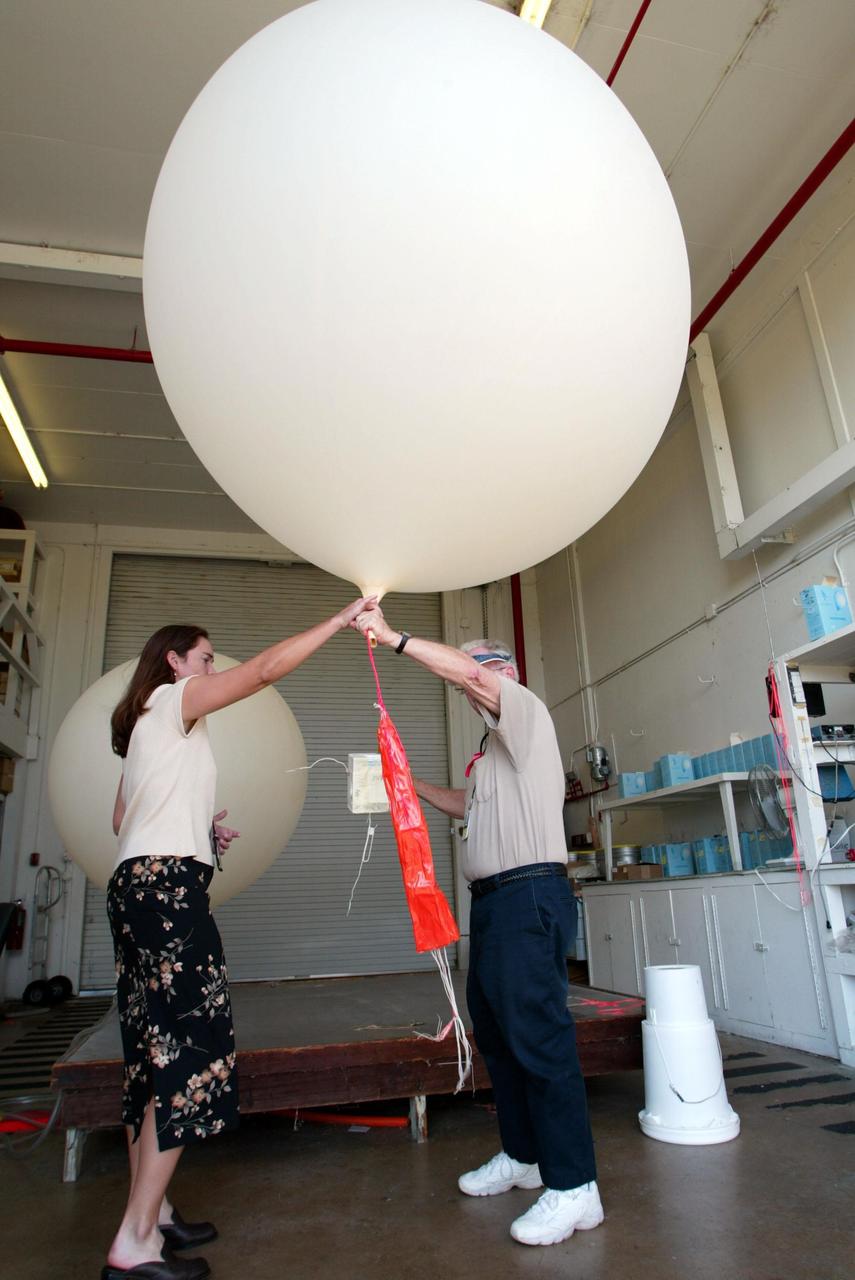KENNEDY SPACE CENTER, FLA. - At Weather Station A, Cape Canaveral Air Force Station, Judy Kelley, supervisor of Meteorology Operations, and Stephen Ezell, meteorological systems operator, get ready to release a weather balloon. Such balloons are released twice a day.  The package at the bottom is a radio sonde that collects temperature and humidity data as the balloon rises.  The data is released to agencies nationwide, including the 45th Space Wing, which uses the data for its daily weather reports.  The weather station provides additional data to NASA for launches -- releasing 12 balloons in eight hours prior to liftoff - and landings - releasing 5 balloons in six and a half hours before expected touchdown.         