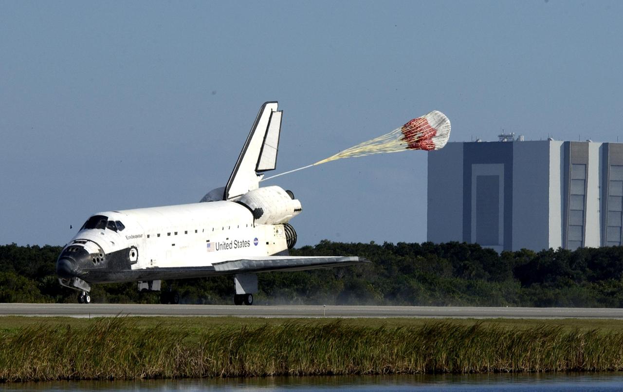 KENNEDY SPACE CENTER, FLA. -  Space Shuttle Endeavour's drag chute deploys as the orbiter lands on runway 33 at the Shuttle Landing Facility after completing the 13-day, 18-hour, 48-minute, 5.74-million mile STS-113 mission to the International Space Station. In the background is a well known KSC landmark: the 525-foot-tall Vehicle Assembly Building.  Main gear touchdown was at 2:37:12 p.m. EST, nose gear touchdown was at 2:37:23 p.m., and wheel stop was at 2:38:25 p.m. Poor weather conditions thwarted landing opportunities until a fourth day, the first time in Shuttle program history that a landing has been waved off for three consecutive days. The vehicle carries the STS-113 crew, Commander James Wetherbee, Pilot Paul Lockhart and Mission Specialists Michael Lopez-Alegria and John Herrington, as well as the returning Expedition Five crew, Commander Valeri Korzun, ISS Science Officer Peggy Whitson and Flight Engineer Sergei Treschev. The installation of the P1 truss on the International Space Station was accomplished during the mission.