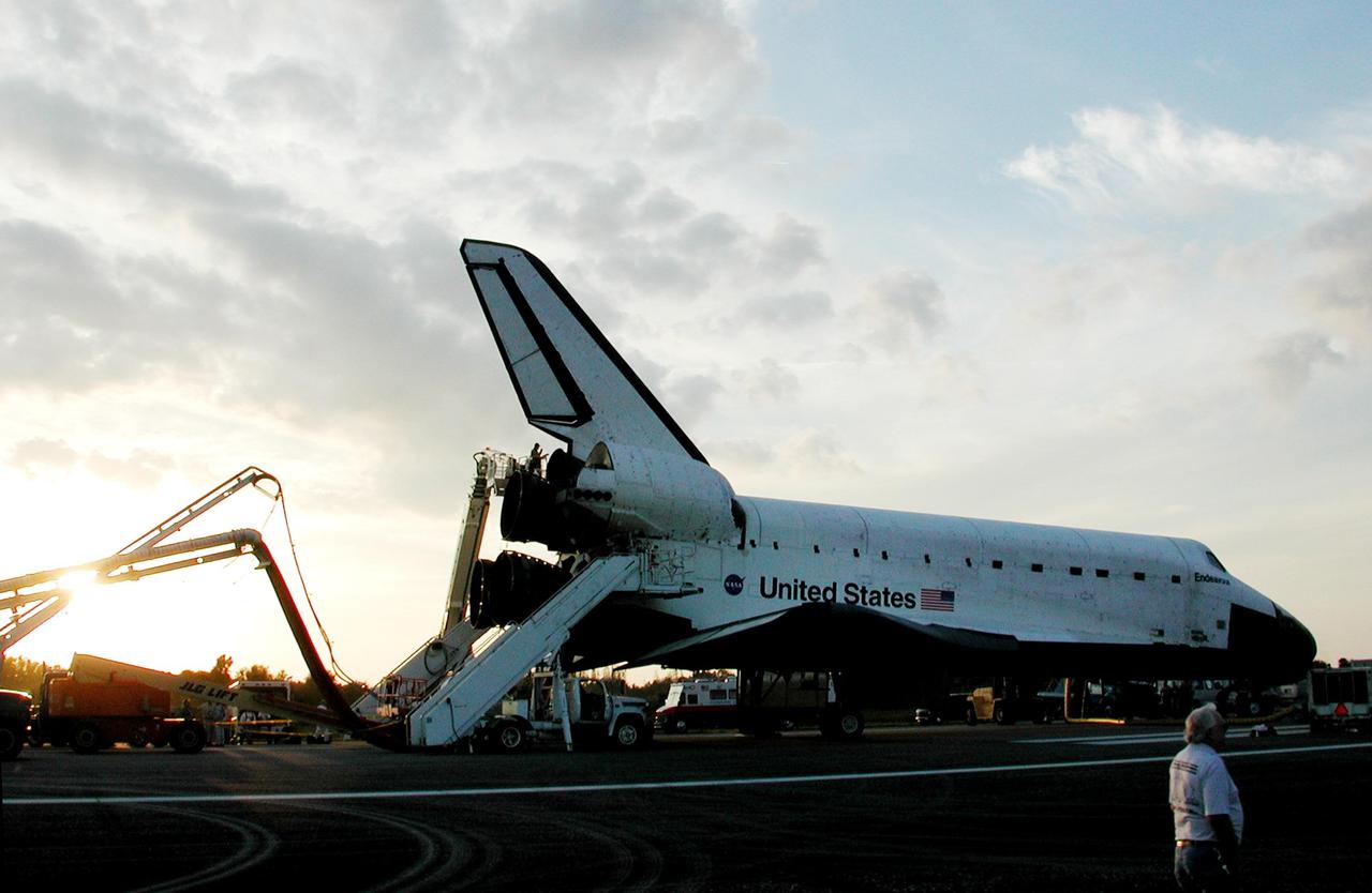 KENNEDY SPACE CENTER, FLA. -  A technician, outlined against the setting sun, checks the main engines on Space Shuttle Endeavour on runway 33 at the Shuttle Landing Facility at the conclusion of the 13-day, 18-hour, 48-minute, 5.74-million mile STS-113 mission to the International Space Station. The landing convoy's purpose is to safe the vehicle and provide support for the disembarking crew and experiments.  Main gear touchdown was at 2:37:12 p.m. EST, nose gear touchdown was at 2:37:23 p.m., and wheel stop was at 2:38:25 p.m. Poor weather conditions thwarted landing opportunities until a fourth day, the first time in Shuttle program history that a landing has been waved off for three consecutive days. The vehicle carries the STS-113 crew, Commander James Wetherbee, Pilot Paul Lockhart and Mission Specialists Michael Lopez-Alegria and John Herrington, as well as the returning Expedition Five crew, Commander Valeri Korzun, ISS Science Officer Peggy Whitson and Flight Engineer Sergei Treschev. The installation of the P1 truss on the International Space Station was accomplished during the mission.