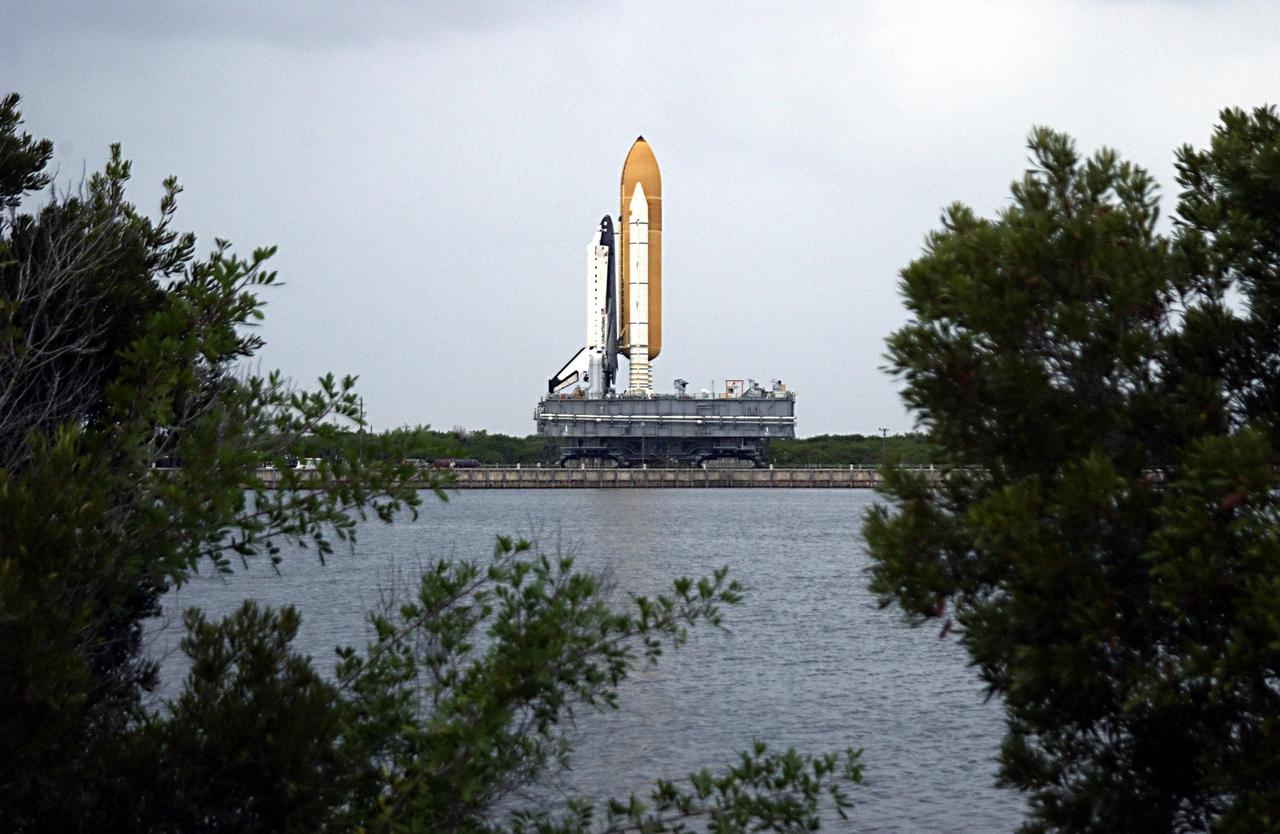 KENNEDY SPACE CENTER, FLA. -- Space Shuttle Columbia, framed by trees near the Banana River, rolls towards Launch Pad 39A, sitting atop the Mobile Launcher Platform, which in turn is carried by the crawler-transporter underneath. The STS-107 research mission comprises experiments ranging from material sciences to life sciences (many rats), plus the Fast Reaction Experiments Enabling Science, Technology, Applications and Research (FREESTAR) that incorporates eight high priority secondary attached shuttle experiments. Mission STS-107 is scheduled to launch Jan. 16, 2003.