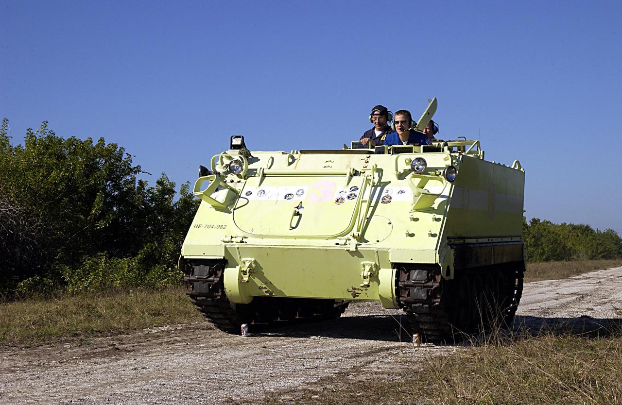KENNEDY SPACE CENTER, FLA. --  -- STS-107 Pilot William "Willie" McCool operates an M113 armored personnel carrier during Terminal Countdown Demonstration Test activities, a standard part of launch preparations.  Instructor George Hoggard (left) supervises the training. STS-107 is a mission devoted to research and will include more than 80 experiments that will study Earth and space science, advanced technology development, and astronaut health and safety. Launch is planned for Jan. 16, 2003, between 10 a.m. and 2 p.m. EST aboard Space Shuttle Columbia.