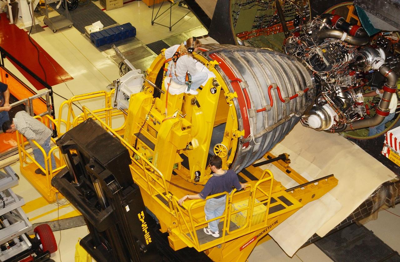 KENNEDY SPACE CENTER, FLA. -- In the Orbiter Processing Facility, workers use a new engine hyster, built by Rocketdyne, to remove an engine on an orbiter. .