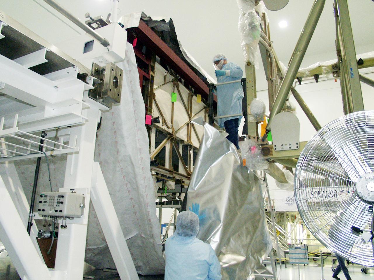 KENNEDY SPACE CENTER, FLA. -- In the Space Station Processing Facility, workers begin uncovering the Long Spacer (LS), the second and final piece of the S6 Integrated Truss Segment. Both the LS and the S6 Integrated Equipment Assembly (IEA) will undergo inspections and verifications tests to prepare them for flight to the International Space Station in early 2004. Although separate for now, the two segments will be integrated and fly as one on mission STS-119. Together the two pieces weigh 26,000 pounds and measure 45 feet long. The S6 is the 11th and final piece of the Station's Integrated Truss Structure, which will measure more than 300 feet in all. .