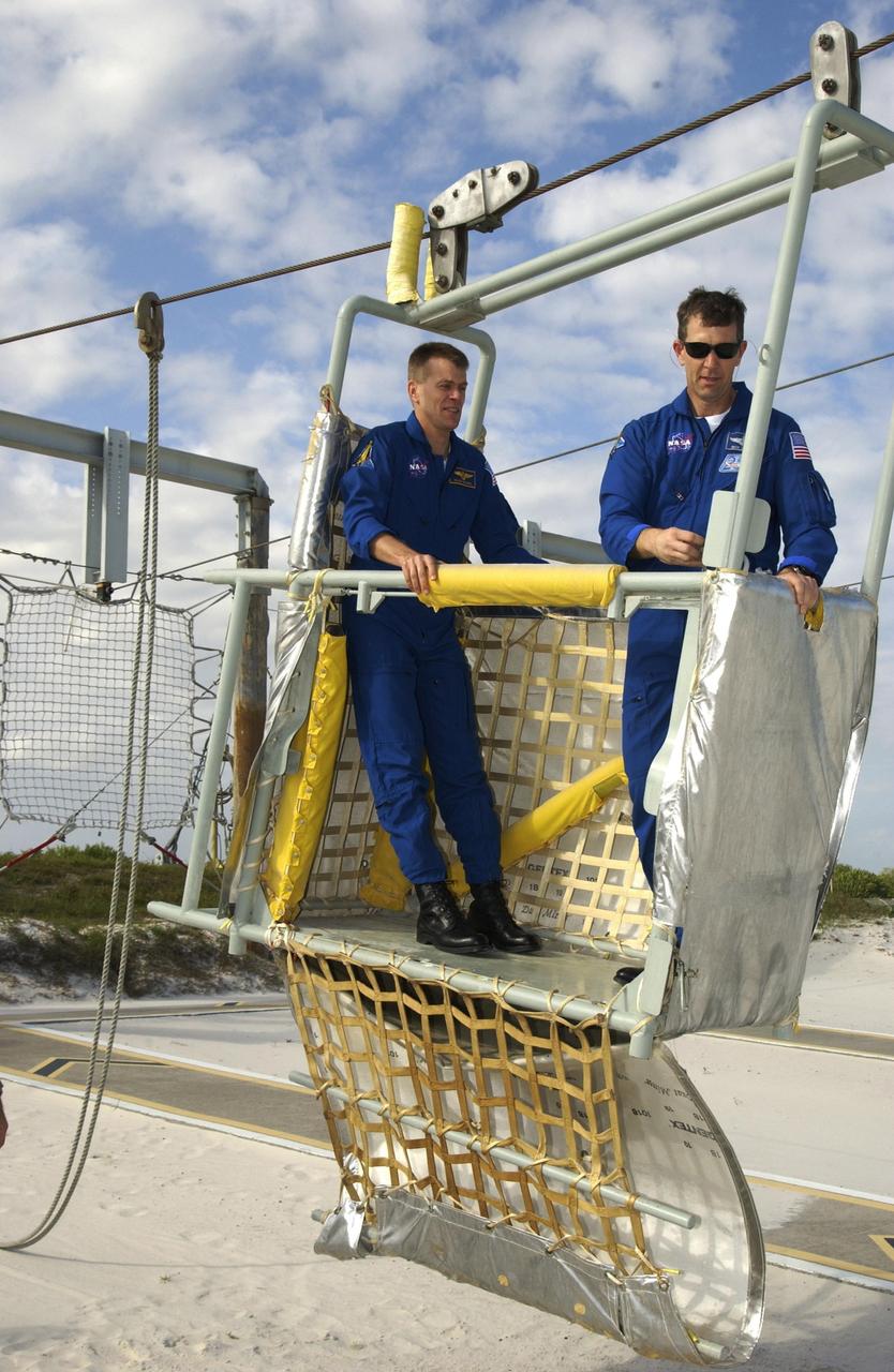 KENNEDY SPACE CENTER, FLA. -- During emergency egress training, part of Terminal Countdown Demonstration Test activities at the pad, STS-107 Pilot William "Willie" McCool and Commander Rick Husband share a slidewire basket. The TCDT also includes a simulated launch countdown.  STS-107 is a mission devoted to research and will include more than 80 experiments that will study Earth and space science, advanced technology development, and astronaut health and safety. Launch is planned for Jan. 16, 2003, between 10 a.m. and 2 p.m. EST aboard Space Shuttle Columbia.    .  