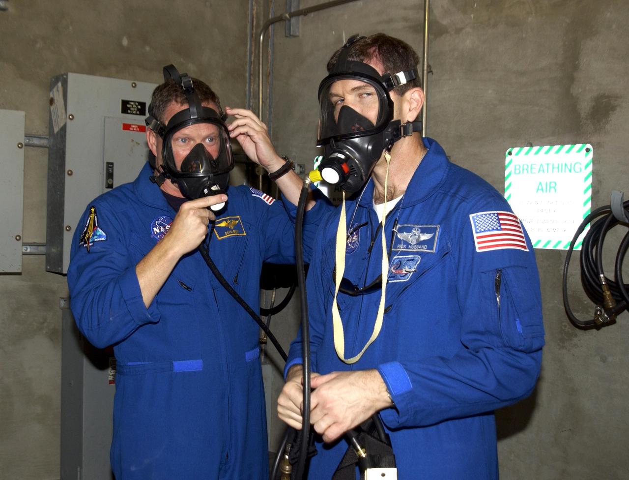 KENNEDY SPACE CENTER, FLA. -- During emergency egress training, part of Terminal Countdown Demonstration Test activities at the pad, STS-107 Mission Specialist David Brown (left) and Commander Rick Husband (right) test breathing masks in the emergency bunker. The TCDT also includes a simulated launch countdown.  STS-107 is a mission devoted to research and will include more than 80 experiments that will study Earth and space science, advanced technology development, and astronaut health and safety. Launch is planned for Jan. 16, 2003, between 10 a.m. and 2 p.m. EST aboard Space Shuttle Columbia.    .  
