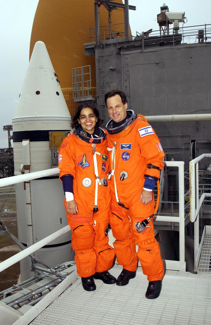 KENNEDY SPACE CENTER, FLA. -- - During Terminal Countdown Demonstration Test activities at the launch pad, Mission Specialists Kalpana Chawla and Ilan Ramon pause for a photo.  Behind them is Space Shuttle Columbia. STS-107 is a mission devoted to research and will include more than 80 experiments that will study Earth and space science, advanced technology development, and astronaut health and safety. Launch is planned for Jan. 16, 2003, between 10 a.m. and 2 p.m. EST aboard Space Shuttle Columbia.        .  