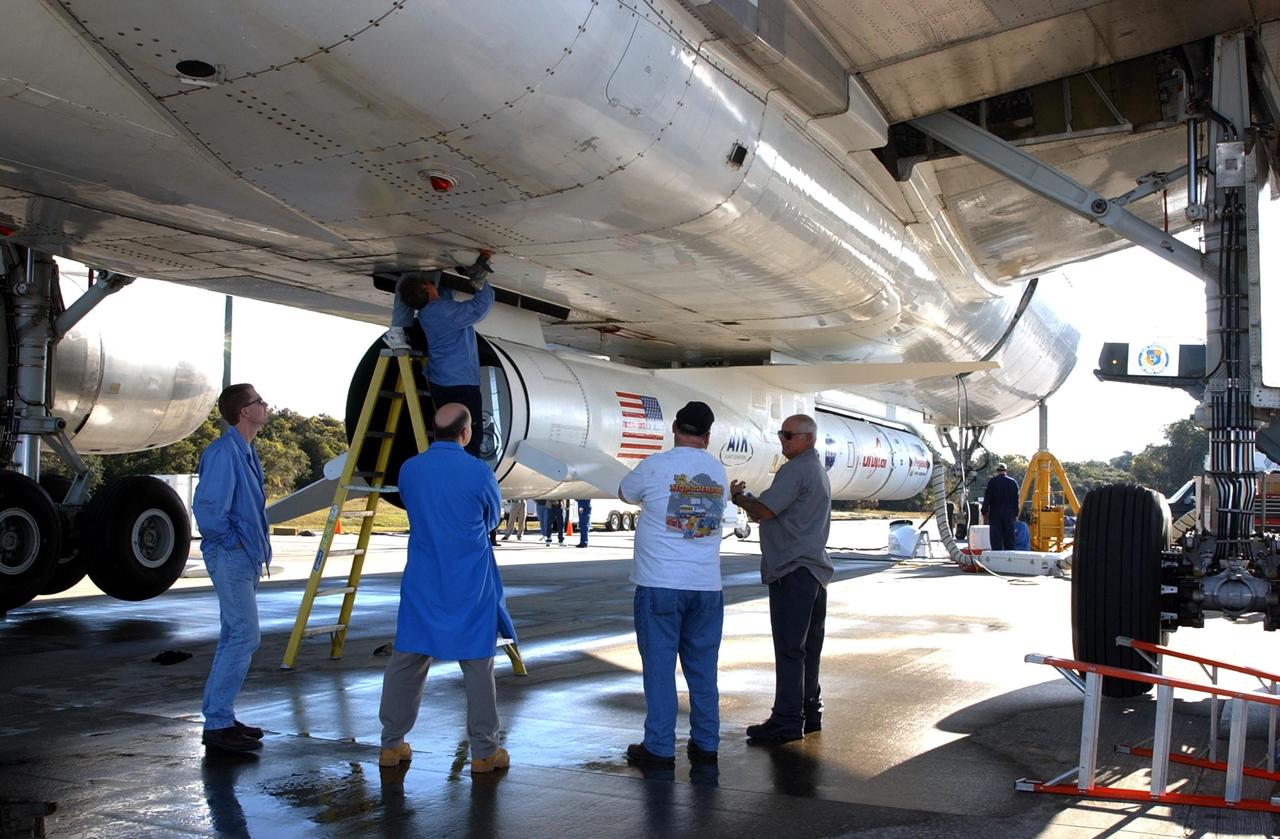 KENNEDY SPACE CENTER, FLA. -- Workers begin the process to remove a Pegasus XL Expendable Launch Vehicle from the underside of an Orbital Sciences L-1011 aircraft. The aircraft, with the launch vehicle attached, arrived at the Cape Canaveral Air Force Station Skid Strip on Dec. 17. The Pegasus XL will undergo three flight simulations prior to its scheduled launch in late January 2003. It will carry NASA's Solar Radiation and Climate Experiment (SORCE) spacecraft into orbit. Built by Orbital Sciences Space Systems Group, SORCE will study and measure solar irradiance as a source of energy in the Earth's atmosphere with instruments built by the University of Colorado's Laboratory for Atmospheric and Space Physics (LASP).