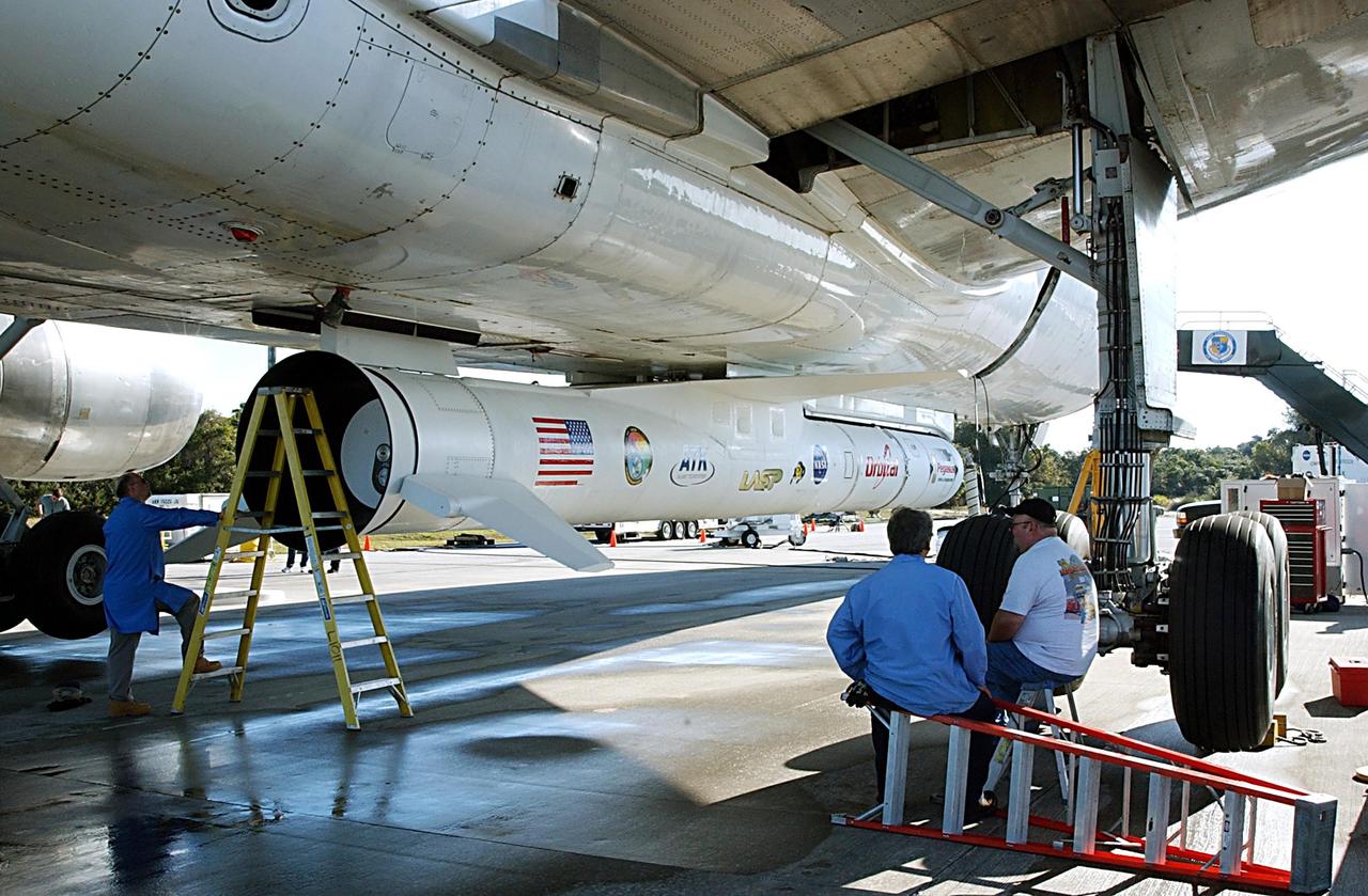 KENNEDY SPACE CENTER, FLA. -- A Pegasus XL Expendable Launch Vehicle is prepared for its removal from the underside of an Orbital Sciences L-1011 aircraft as onlooking workers await their turns in the process. The aircraft, with the launch vehicle attached, arrived at the Cape Canaveral Air Force Station Skid Strip on Dec. 17. The Pegasus XL will undergo three flight simulations prior to its scheduled launch in late January 2003. It will carry NASA's Solar Radiation and Climate Experiment (SORCE) spacecraft into orbit. Built by Orbital Sciences Space Systems Group, SORCE will study and measure solar irradiance as a source of energy in the Earth's atmosphere with instruments built by the University of Colorado's Laboratory for Atmospheric and Space Physics (LASP).