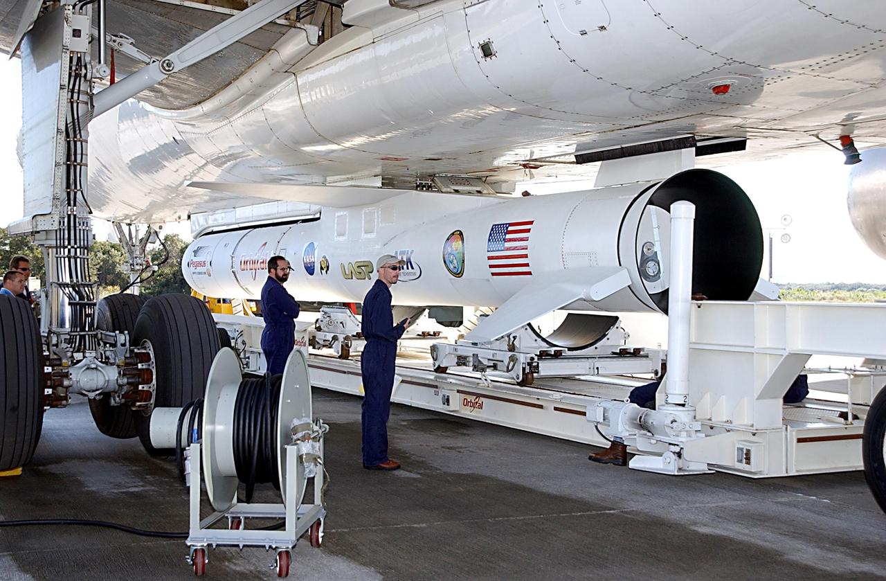 KENNEDY SPACE CENTER, FLA. -- Workers supervise the placement of a transporter below a Pegasus XL Expendable Launch Vehicle before its detachment from the underside of an Orbital Sciences L-1011 aircraft. The aircraft, with the launch vehicle nestled beneath, arrived at the Cape Canaveral Air Force Station Skid Strip on Dec. 17. The Pegasus XL will undergo three flight simulations prior to its scheduled launch in late January 2003. It will carry NASA's Solar Radiation and Climate Experiment (SORCE) spacecraft into orbit. Built by Orbital Sciences Space Systems Group, SORCE will study and measure solar irradiance as a source of energy in the Earth's atmosphere with instruments built by the University of Colorado's Laboratory for Atmospheric and Space Physics (LASP).