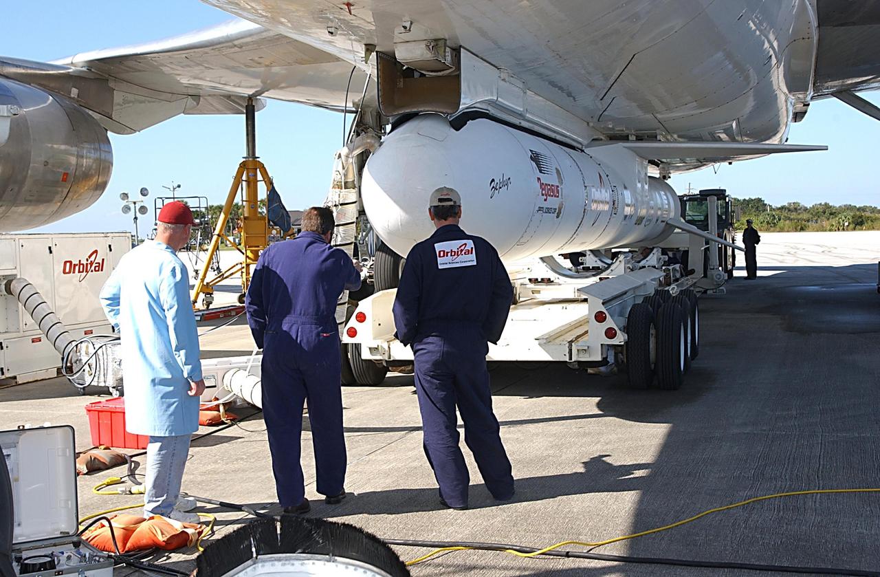 KENNEDY SPACE CENTER, FLA. -- Workers evaluate the placement of a transporter below a Pegasus XL Expendable Launch Vehicle before its detachment from the underside of an Orbital Sciences L-1011 aircraft. The aircraft, with the launch vehicle nestled beneath, arrived at the Cape Canaveral Air Force Station Skid Strip on Dec. 17. The Pegasus XL will undergo three flight simulations prior to its scheduled launch in late January 2003. It will carry NASA's Solar Radiation and Climate Experiment (SORCE) spacecraft into orbit. Built by Orbital Sciences Space Systems Group, SORCE will study and measure solar irradiance as a source of energy in the Earth's atmosphere with instruments built by the University of Colorado's Laboratory for Atmospheric and Space Physics (LASP).