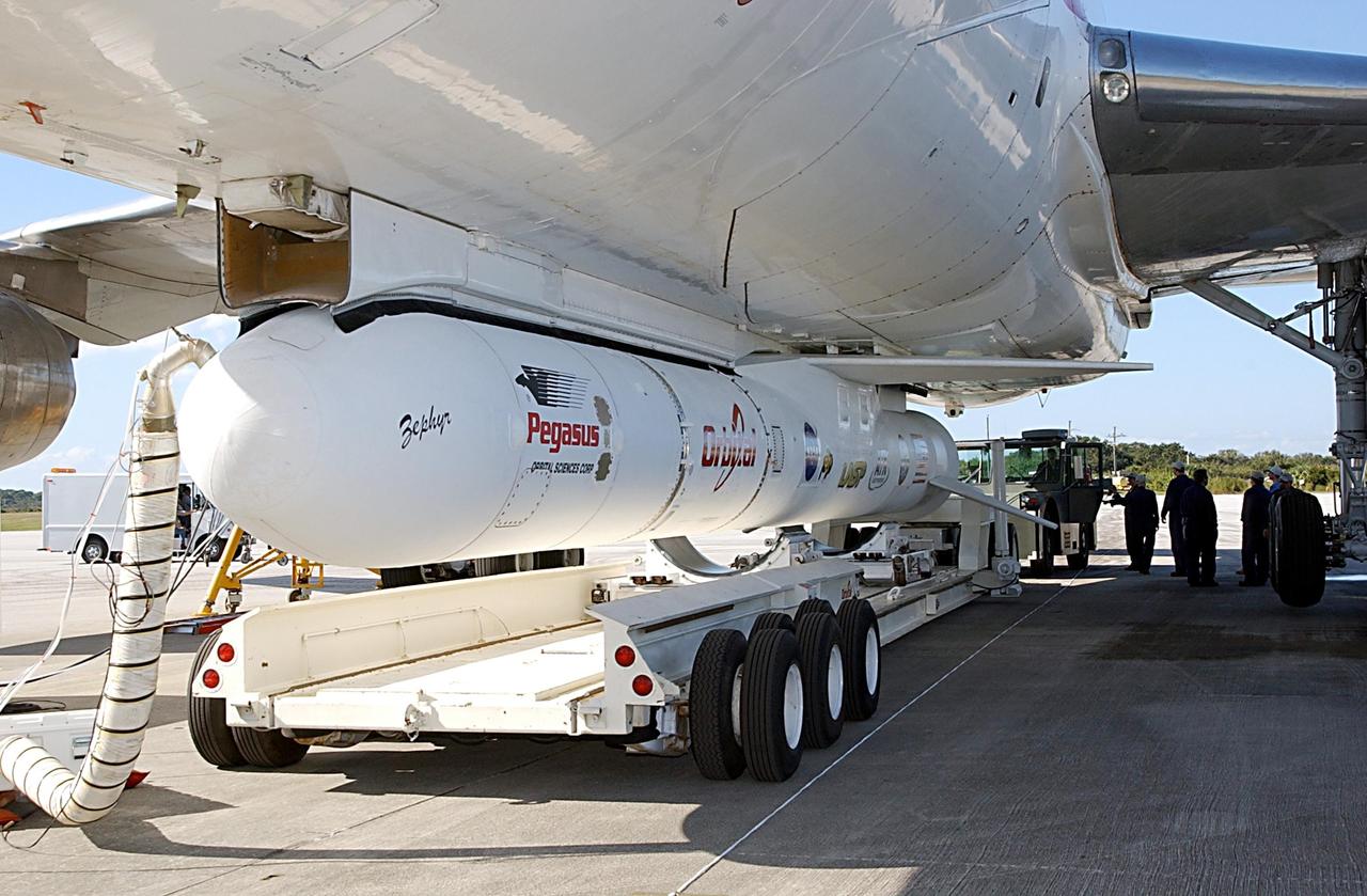 KENNEDY SPACE CENTER, FLA. -- A transporter is repositioned below a Pegasus XL Expendable Launch Vehicle before it is detached from the underside of an Orbital Sciences L-1011 aircraft. The aircraft, with the launch vehicle nestled beneath, arrived at the Cape Canaveral Air Force Station Skid Strip on Dec. 17. The Pegasus XL will undergo three flight simulations prior to its scheduled launch in late January 2003. It will carry NASA's Solar Radiation and Climate Experiment (SORCE) spacecraft into orbit. Built by Orbital Sciences Space Systems Group, SORCE will study and measure solar irradiance as a source of energy in the Earth's atmosphere with instruments built by the University of Colorado's Laboratory for Atmospheric and Space Physics (LASP).