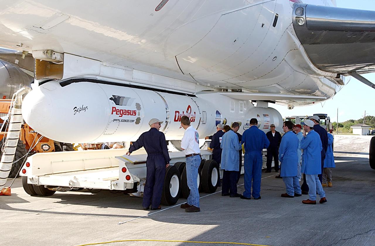 KENNEDY SPACE CENTER, FLA. -- Workers reevaluate the placement of a transporter below a Pegasus XL Expendable Launch Vehicle before its detachment from the underside of an Orbital Sciences L-1011 aircraft. The aircraft, with the launch vehicle nestled beneath, arrived at the Cape Canaveral Air Force Station Skid Strip on Dec. 17. The Pegasus XL will undergo three flight simulations prior to its scheduled launch in late January 2003. It will carry NASA's Solar Radiation and Climate Experiment (SORCE) spacecraft into orbit. Built by Orbital Sciences Space Systems Group, SORCE will study and measure solar irradiance as a source of energy in the Earth's atmosphere with instruments built by the University of Colorado's Laboratory for Atmospheric and Space Physics (LASP).