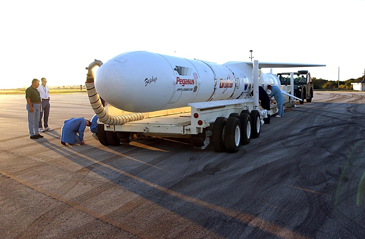 KENNEDY SPACE CENTER, FLA. -- A Pegasus XL Expendable Launch Vehicle is prepared for towing to the Multi-Purpose Payload Facility (MPPF) where it will undergo testing, verification, and three flight simulations prior to its scheduled launch. The vehicle, nestled beneath an Orbital Sciences L-1011 aircraft, arrived at the Cape Canaveral Air Force Station Skid Strip on Dec. 17. It is commissioned to carry NASA's Solar Radiation and Climate Experiment (SORCE) spacecraft into orbit in late January 2003. Built by Orbital Sciences Space Systems Group, SORCE will study and measure solar irradiance as a source of energy in the Earth's atmosphere with instruments built by the University of Colorado's Laboratory for Atmospheric and Space Physics (LASP).