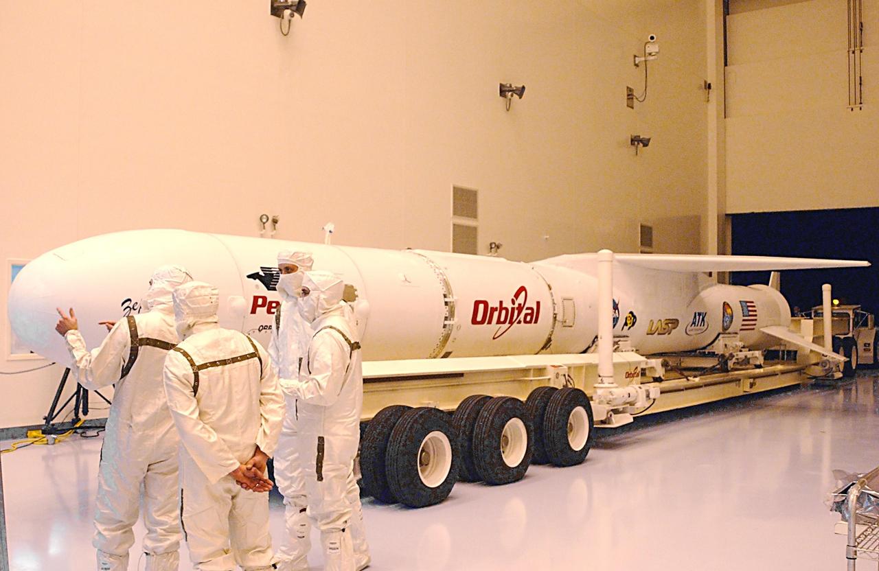 KENNEDY SPACE CENTER, FLA. -- Workers in clean room attire supervise the delivery of a Pegasus XL Expendable Launch Vehicle to the Multi-Purpose Payload Facility (MPPF).  Next, it will be moved into a highbay where it will undergo testing, verification, and three flight simulations prior to its scheduled launch. The vehicle, nestled beneath an Orbital Sciences L-1011 aircraft, arrived at the Cape Canaveral Air Force Station Skid Strip on Dec. 17.  It is commissioned to carry NASA's Solar Radiation and Climate Experiment (SORCE) spacecraft into orbit in late January 2003. Built by Orbital Sciences Space Systems Group, SORCE will study and measure solar irradiance as a source of energy in the Earth's atmosphere with four instruments built by the University of Colorado's Laboratory for Atmospheric and Space Physics (LASP).