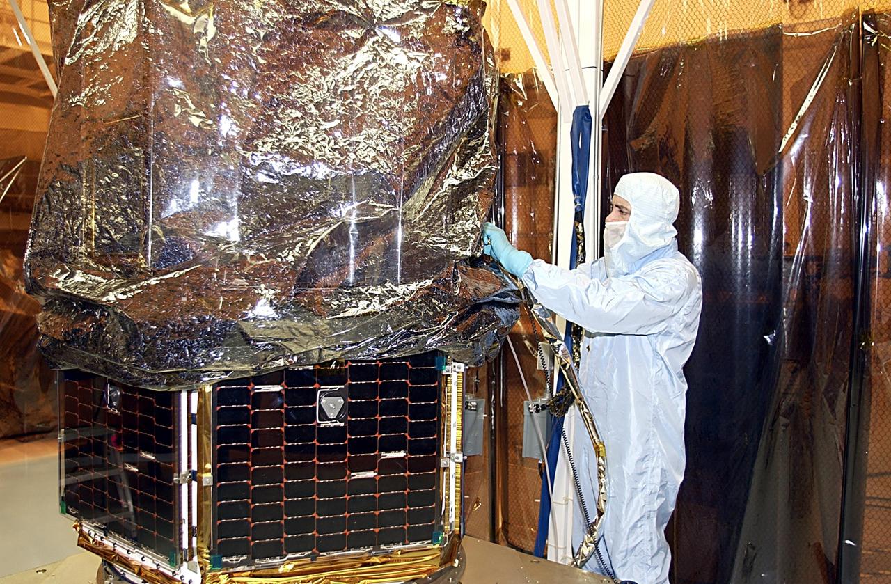 KENNEDY SPACE CENTER, FLA. - A worker adjusts the protective cover on the SORCE satellite before its move to a rotating workstand and mating to the Pegasus launch vehicle. SORCE is equipped with four instruments that will measure variations in solar radiation and observe some spectral properties of solar radiation for the first time. With data from NASA's SORCE mission, researchers should be able to follow how the Sun affects our climate now and in the future. Launch of SORCE aboard the Pegasus XL rocket is scheduled for Jan. 25, 2003, at approximately 3:14 p.m. EST, from Cape Canaveral Air Force Station, Fla.