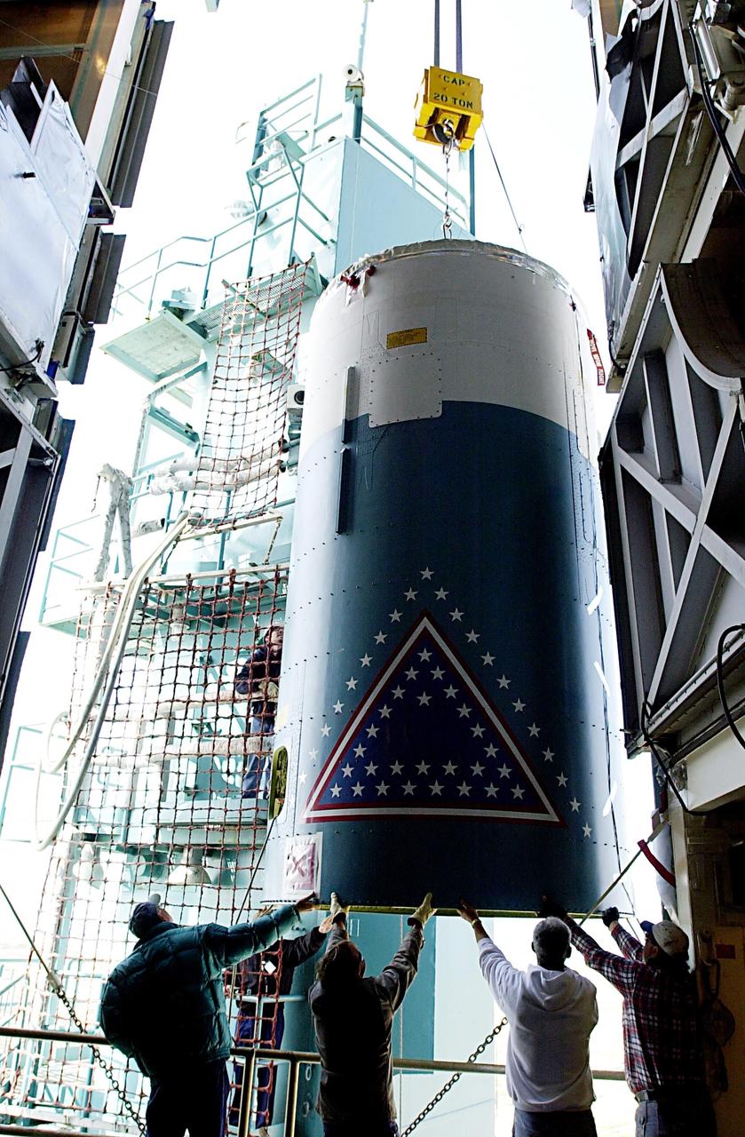 KENNEDY SPACE CENTER, FLA. - Workers on the launch tower on NASA's Space Launch Complex 2 (SLC-2), Vandenberg Air Force Base, Calif., help guide the interstage of the Delta II rocket into position for mating with the first stage. The rocket will carry the ICESat and CHIPSat satellites into Earth orbits. ICESat is a 661-pound satellite known as Geoscience Laser Altimeter System (GLAS) that will revolutionize our understanding of ice and its role in global climate change and how we protect and understand our home planet. It will help scientists determine if the global sea level is rising or falling. It will look at the ice sheets that blanket the Earth's poles to see if they are growing or shrinking. It will assist in developing an understanding of how changes in the Earth's atmosphere and climate effect polar ice masses and global sea level. CHIPSat, a suitcase-size 131-pound satellite, will provide invaluable information into the origin, physical processes and properties of the hot gas contained in the interstellar medium. This can provide important clues about the formation and evolution of galaxies since the interstellar medium literally contains the seeds of future stars. The Delta II launch is scheduled for Jan. 11 between 4:45 p.m. - 5:30 p.m. PST.
