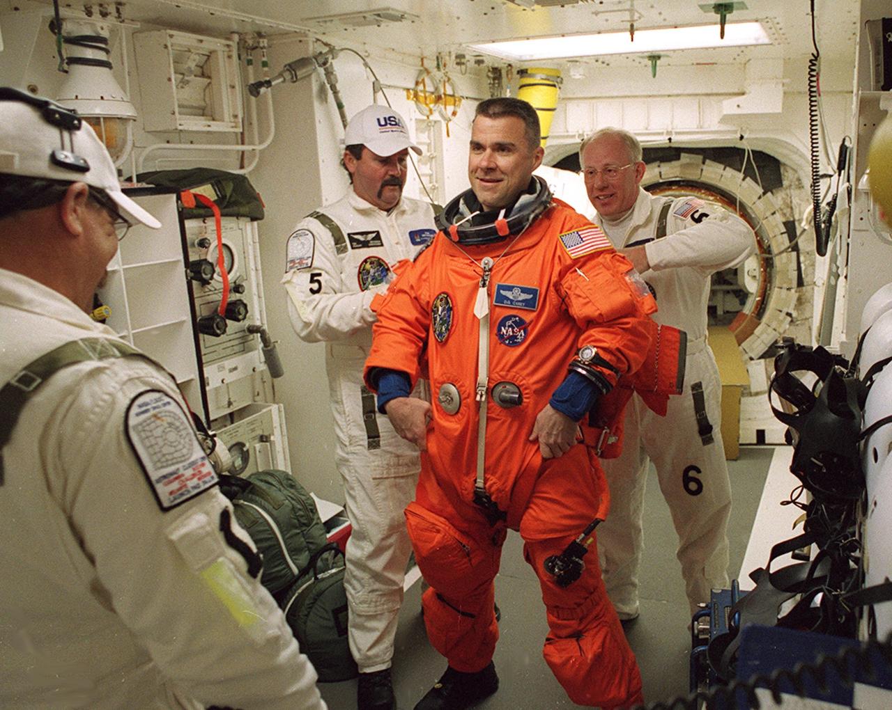 KENNEDY SPACE CENTER, FLA. -  In the White Room, STS-109 Pilot Duane G. Carey (center) is helped with his launch and entry suit by Tim Seymour (left), United Space Alliance mechanical technician, and Danny Wyatt (right), NASA quality assurance specialist.  On the mission, Space Shuttle Columbia will rendezvous with the Hubble Space Telescope for the crew to replace and upgrade key telescope systems through five challenging spacewalks.  After an extensive 2-1/2 year modification period during which many systems were replaced and enhanced, Columbia is making its 27th flight in the Shuttle program.  After the 11-day mission, Columbia is expected to land at Kennedy Space Center March 12