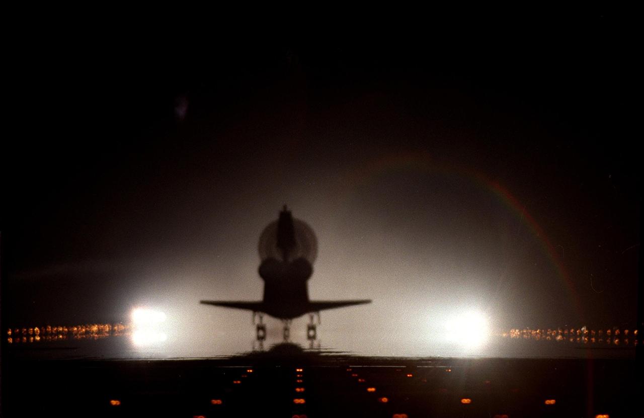 KENNEDY SPACE CENTER, FLA. --  With its drag chute opened, orbiter Columbia is silhouetted against the brilliant xenon lights at the KSC Shuttle Landing Facility. Columbia landed at 4:33:09 a.m. EST with its crew of seven after a successful 11-day mission servicing the Hubble Space Telescope. Main gear touchdown occurred at 4:31:52 a.m. and nose wheel touchdown at 4:32:02.  Rollout time was 1 minute, 17 seconds.   This was the 58th landing at KSC out of 108 missions in the history of the Shuttle program.