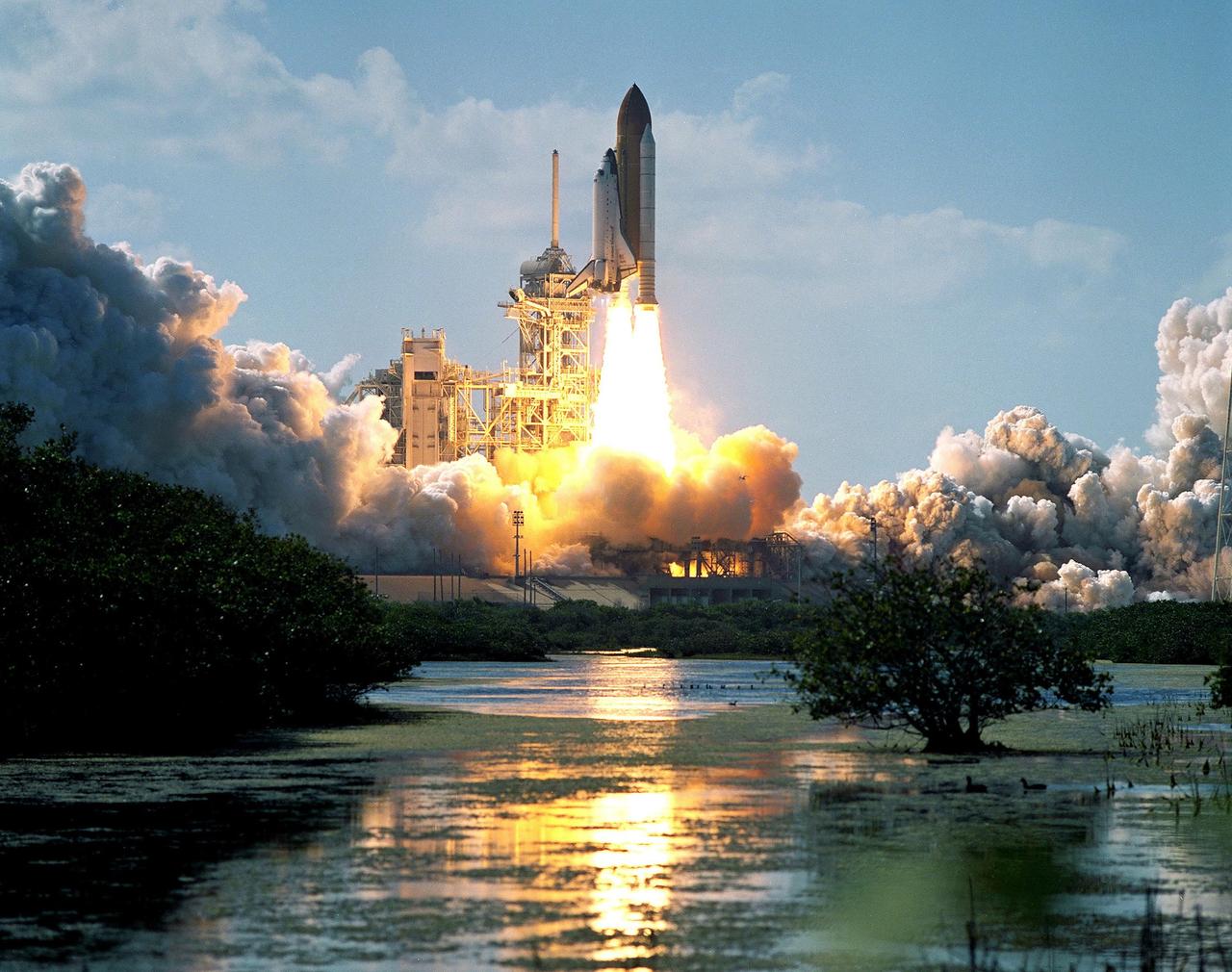 KENNEDY SPACE CENTER, FLA. -  Billowing clouds of smoke and steam roll away from the launch pad while the water below captures the brilliance of the flames as Space Shuttle Atlantis soars above the lightning mast on mission STS-110. Liftoff occurred at 4:44:19 p.m. EDT (20:41:19 GMT).  Carrying the S0 Integrated Truss Structure and Mobile Transporter, STS-110 is the 13th assembly flight to the International Space Station.