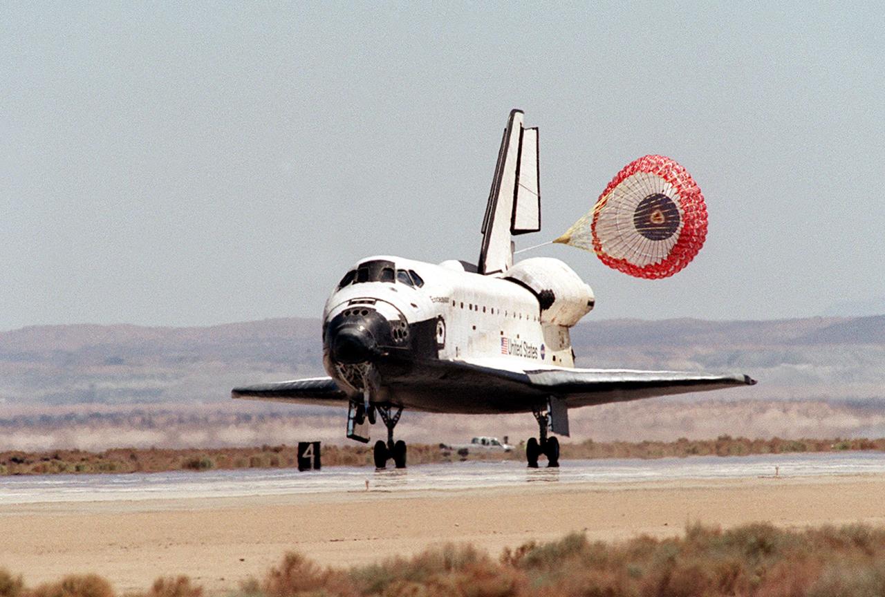 EDWARDS AFB, CALIF. -- After traveling 5.8 million miles in space during 217 orbits, and with drag chute deployed, Endeavour lands on concrete runway 22 at Dryden Flight Research Center, Edwards Air Force Base, Calif., completing mission STS-111. Three days of unfavorable weather conditions at KSC prompted the decision to land at Edwards, which enjoyed pristine, dry conditions.. Main gear touchdown occurred at 1:57:41 p.m. EDT, nose gear touchdown at 1:57:53 p.m. EDT and wheel stop at 1:58:45 p.m. EDT. [Photo by Jim Ross]