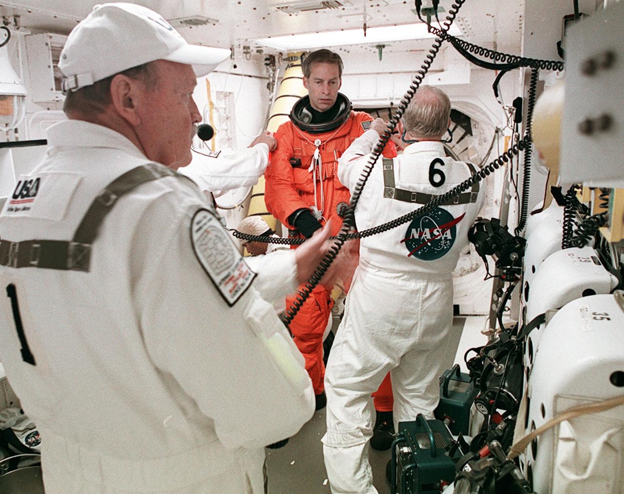 KENNEDY SPACE CENTER, FLA. - In the White Room on Launch Pad 39A, STS-113 Commander Jim Wetherbee is helped with his launch and entry suit before entering Space Shuttle Endeavour. Closeout Crew members helping are (left) Rick Welty, United Space Alliance Vehicle Closeout chief, and (right) Danny Wyatt, NASA Quality Assurance specialist. The launch will carry the Expedition 6 crew to the Station and return the Expedition 5 crew to Earth. The major objective of the mission is delivery of the Port 1 (P1) Integrated Truss Assembly, which will be attached to the port side of the S0 truss. Three spacewalks are planned to install and activate the truss and its associated equipment. Launch of Space Shuttle Endeavour on mission STS-113 is scheduled for Nov. 23 at 7:50 p.m. EST.