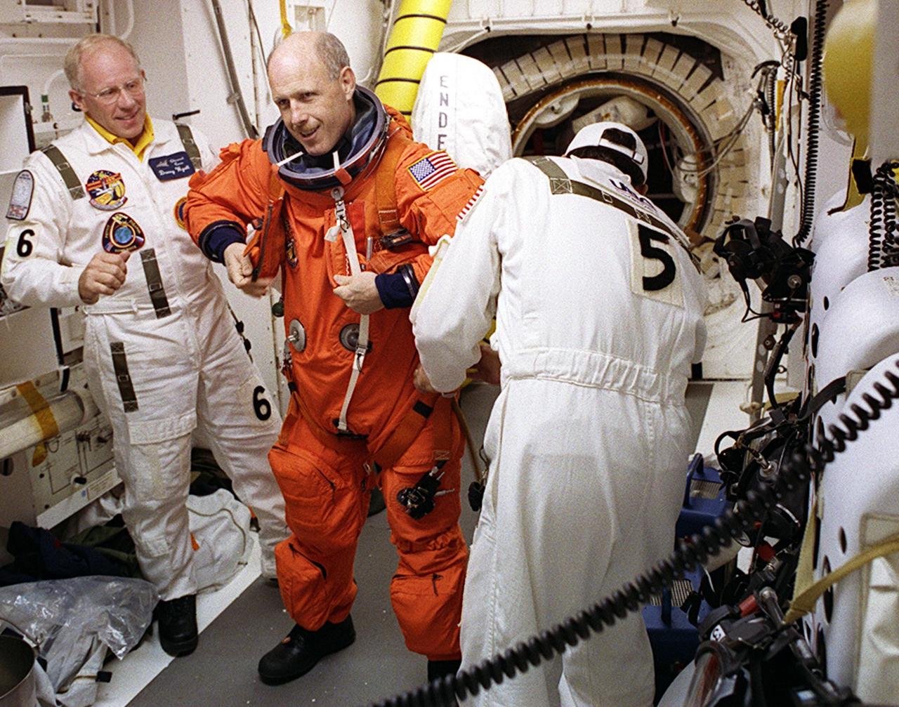 KENNEDY SPACE CENTER, FLA. - In the White Room on Launch Pad 39A, Expedition 6 Commander Ken Bowersox is helped ) with his launch and entry suit before entering Space Shuttle Endeavour. Members of the Closeout Crew helping are (left) Danny Wyatt, NASA Quality Assurance specialist, and (right) Bobby Wright, United Space Alliance mechanical technician. The launch will carry the Expedition 6 crew to the Station and return the Expedition 5 crew to Earth. The major objective of the mission is delivery of the Port 1 (P1) Integrated Truss Assembly, which will be attached to the port side of the S0 truss. Three spacewalks are planned to install and activate the truss and its associated equipment. Launch of Space Shuttle Endeavour on mission STS-113 is scheduled for Nov. 23 at 7:50 p.m. EST.