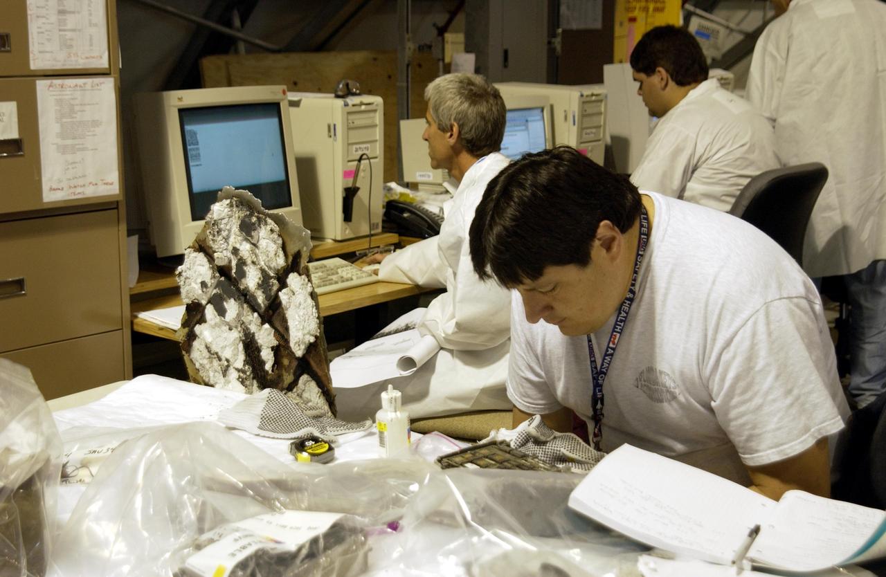 Columbia Reconstruction Project Team members study debris from the Space Shuttle Columbia in the RLV Hangar. The debris is being shipped to KSC from the collection point at Barksdale Air Force Base, Shreveport, La. As part of the ongoing investigation into the tragic accident that claimed Columbia and her crew of seven, workers will attempt to reconstruct the orbiter inside the hangar.