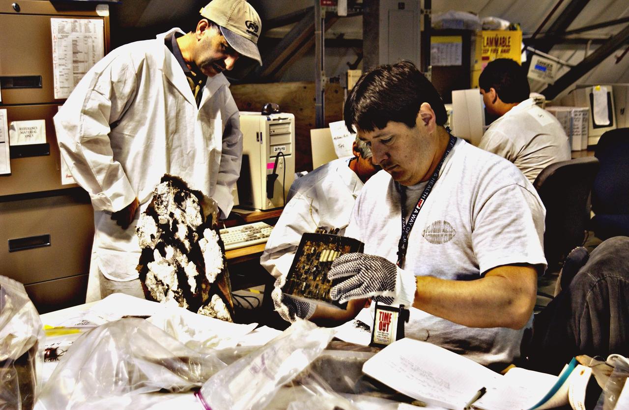 Columbia Reconstruction Project Team members study debris from the Space Shuttle Columbia in the RLV Hangar. The debris is being shipped to KSC from the collection point at Barksdale Air Force Base, Shreveport, La. As part of the ongoing investigation into the tragic accident that claimed Columbia and her crew of seven, workers will attempt to reconstruct the orbiter inside the hangar.