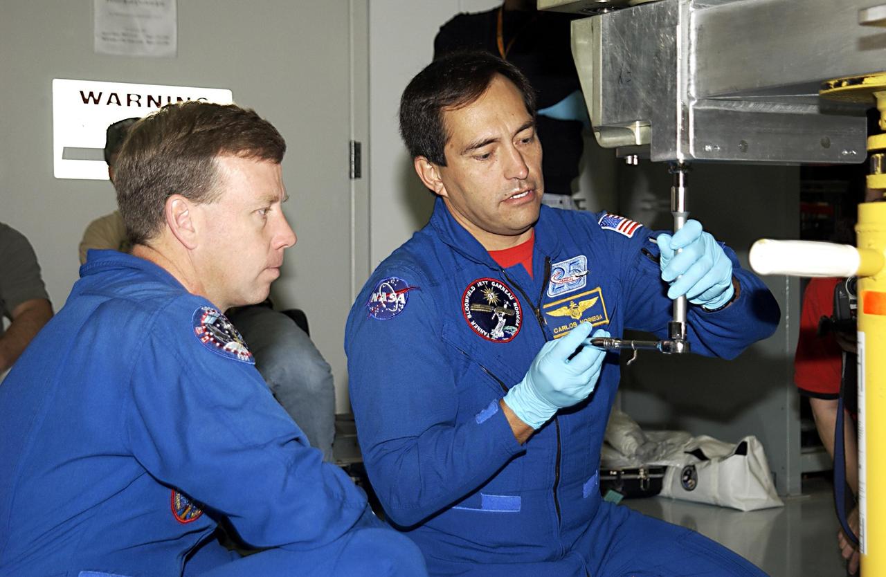 KENNEDY SPACE CENTER, FLA. - During a Crew Equipment Interface Test activity, STS-119 Commander Steven Lindsey watches as Mission Specialist Carlos Noriega works with a tool on the equipment that will be part of the mission. Scheduled to launch in January 2004, the mission will deliver the fourth and final set of U.S. solar arrays along with the fourth starboard truss segment, the S6 truss.    