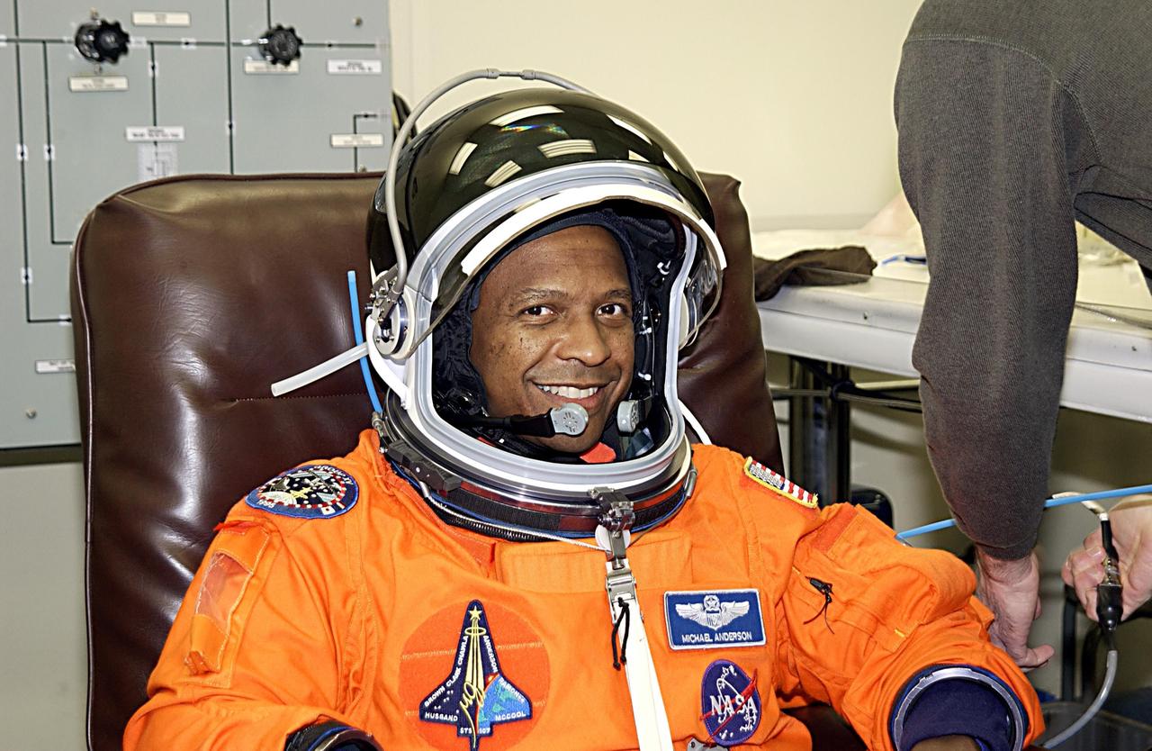 KENNEDY SPACE CENTER, FLA. - STS-107 Payload Commander Michael Anderson is helped with suit check, part of launch preparations. STS-107 is a mission devoted to research and will include more than 80 experiments that will study Earth and space science, advanced technology development, and astronaut health and safety. The payload on Space Shuttle Columbia includes FREESTAR (Fast Reaction Experiments Enabling Science, Technology, Applications and Research) and the SHI Research Double Module (SHI/RDM), known as SPACEHAB.  Experiments on the module range from material sciences to life sciences.  Launch is scheduled for Jan. 16, between 10 a.m. and 2 p.m.