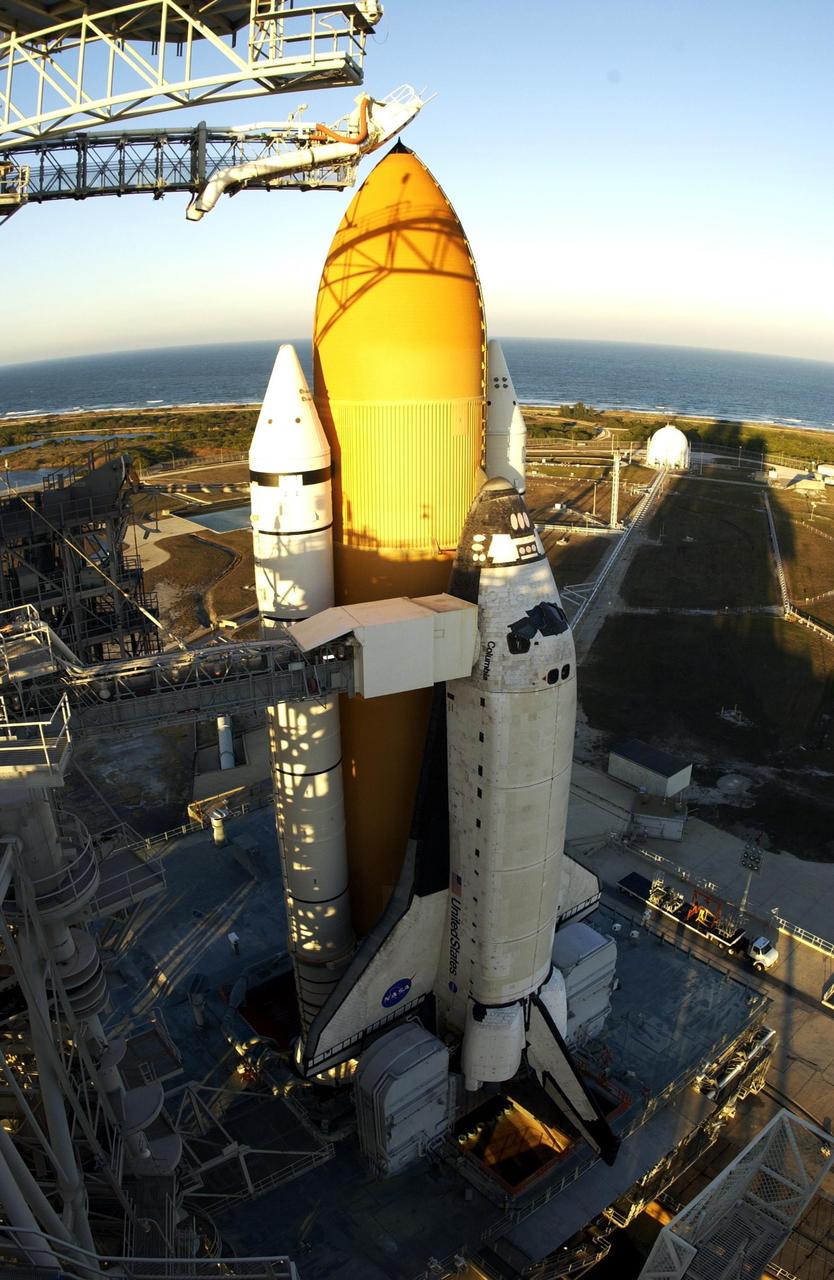 KENNEDY SPACE CENTER, FLA. -- After rollback of the Rotating Service Structure on Launch Pad 39A, the top of Space Shuttle Columbia's external tank and solid rocket booster are bathed in sunlight.  Shadows from the Fixed Service Structure stretch across the Shuttle and landscape. Visible are the orbiter access arm with the White Room extended to Columbia's cockpit, and at the top, the gaseous oxygen vent arm and cap, called the "beanie cap." Columbia is scheduled for launch Jan. 16 at 10:39 a.m. EST on mission STS-107, a research mission.      