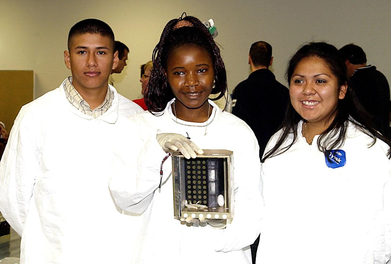 KENNEDY SPACE CENTER, FLA. -- Students show off one of the experiments that will fly in SPACEHAB on Space Shuttle Columbia on mission STS-107. SPACEHAB's complement of commercial experiments includes six educational experiments designed and developed by students in six different countries under the auspices of Space Technology and Research Students (STARS), a global education program managed by SPACEHAB subsidiary Space Media. The countries represented are Australia, China, Israel, Japan, Liechtenstein and the United States. The student investigators who conceived these experiments will monitor their operations in space. The experiments will be housed in BioServe Space Technologies' Isothermal Containment Module (ICM --a small temperature-controlled facility that provides experiment support such as physical containment, lighting, and video imaging) and stowed in a middeck-size locker aboard the SPACEHAB Research Double Module.