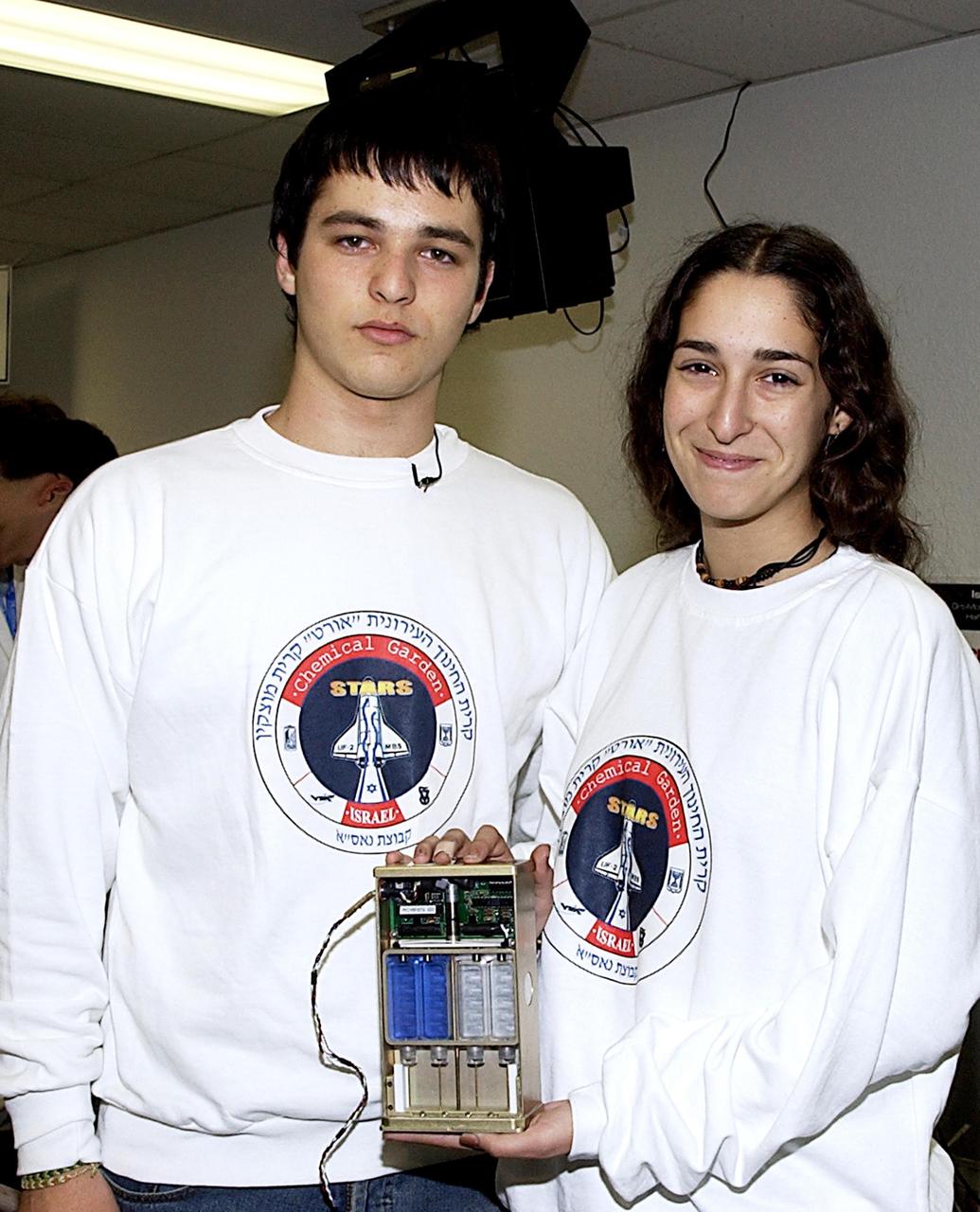 KENNEDY SPACE CENTER, FLA. -- Students show off one of the experiments that will fly in SPACEHAB on Space Shuttle Columbia on mission STS-107. SPACEHAB's complement of commercial experiments includes six educational experiments designed and developed by students in six different countries under the auspices of Space Technology and Research Students (STARS), a global education program managed by SPACEHAB subsidiary Space Media. The countries represented are Australia, China, Israel, Japan, Liechtenstein and the United States. The student investigators who conceived these experiments will monitor their operations in space. The experiments will be housed in BioServe Space Technologies' Isothermal Containment Module (ICM --a small temperature-controlled facility that provides experiment support such as physical containment, lighting, and video imaging) and stowed in a middeck-size locker aboard the SPACEHAB Research Double Module.