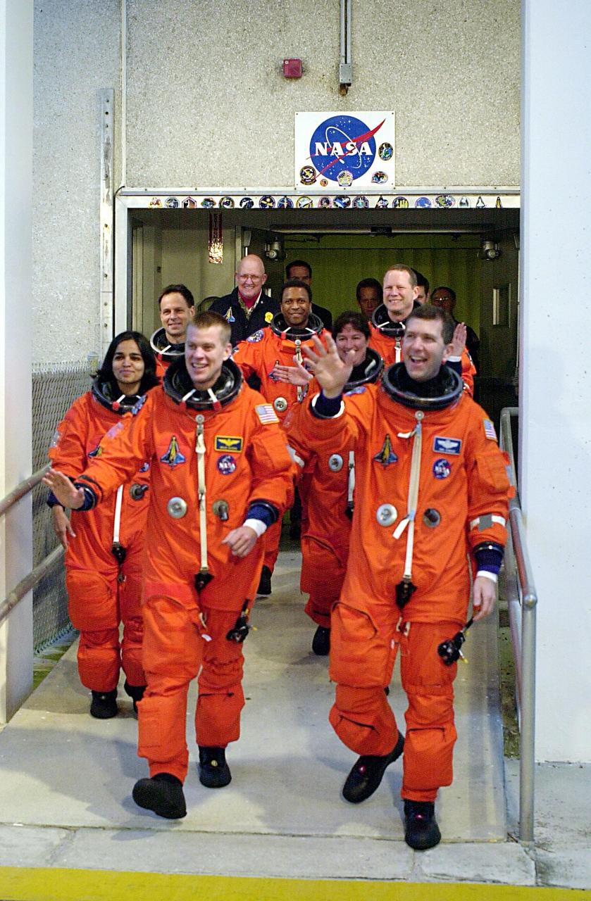 KENNEDY SPACE CENTER, FLA. -- The STS-107 crew, waving to onlookers, exits the Operations and Checkout Building on their way to Launch Pad 39A for liftoff. Leading the way are Pilot William "Willie" McCool (left) and Commander Rick Husband (right). Following in the second row are Mission Specialists Kalpana Chawla (left) and Laurel Clark; in the rear are Payload Specialist Ilan Ramon, Payload Commander Michael Anderson and Mission Specialist David Brown. Ramon is the first astronaut from Israel to fly on a Shuttle. The 16-day mission is devoted to research and will include more than 80 experiments that will study Earth and space science, advanced technology development, and astronaut health and safety. The payload on Space Shuttle Columbia includes FREESTAR (Fast Reaction Experiments Enabling Science, Technology, Applications and Research) and the SHI Research Double Module (SHI/RDM), known as SPACEHAB. Experiments on the module range from material sciences to life sciences. Liftoff is scheduled for 10:39 a.m. EST.