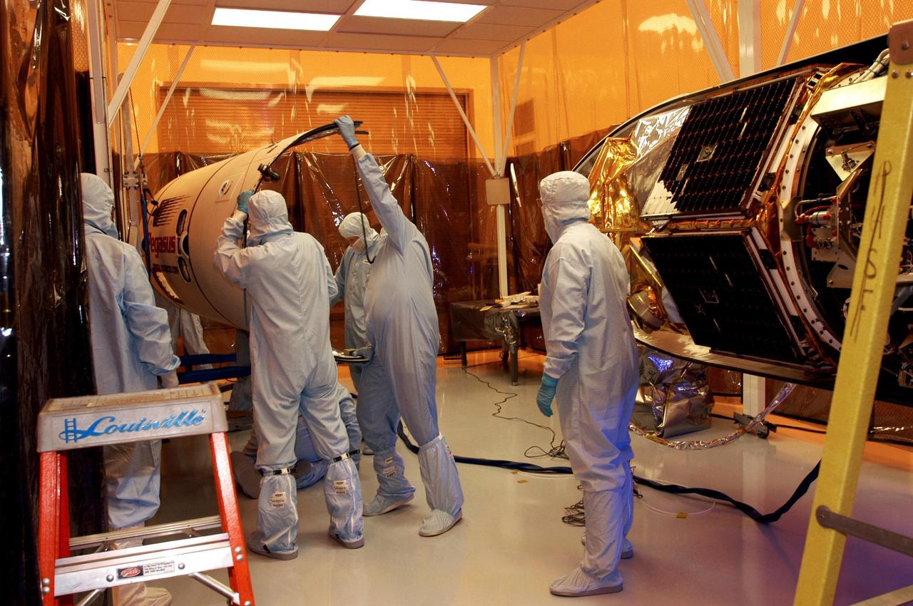 KENNEDY SPACE CENTER, FLA. -- Workers in the Multi-Purpose Processing Facility move part of the fairing toward the Solar Radiation and Climate Experiment (SORCE) satellite for encapsulation. The satellite will be installed in the Pegasus XL launch vehicle. Built by Orbital Sciences Corporation (OSC), SORCE will study and measure solar irradiance as a source of energy in the Earth's atmosphere. The launch of SORCE is scheduled for Jan. 25 at 3:14 p.m. from Cape Canaveral Air Force Station, Fla. The drop of the Pegasus will be from OSC's L-1011 aircraft at an altitude of 39,000 feet over the Atlantic Ocean approximately 100 miles east-southeast of Cape Canaveral.