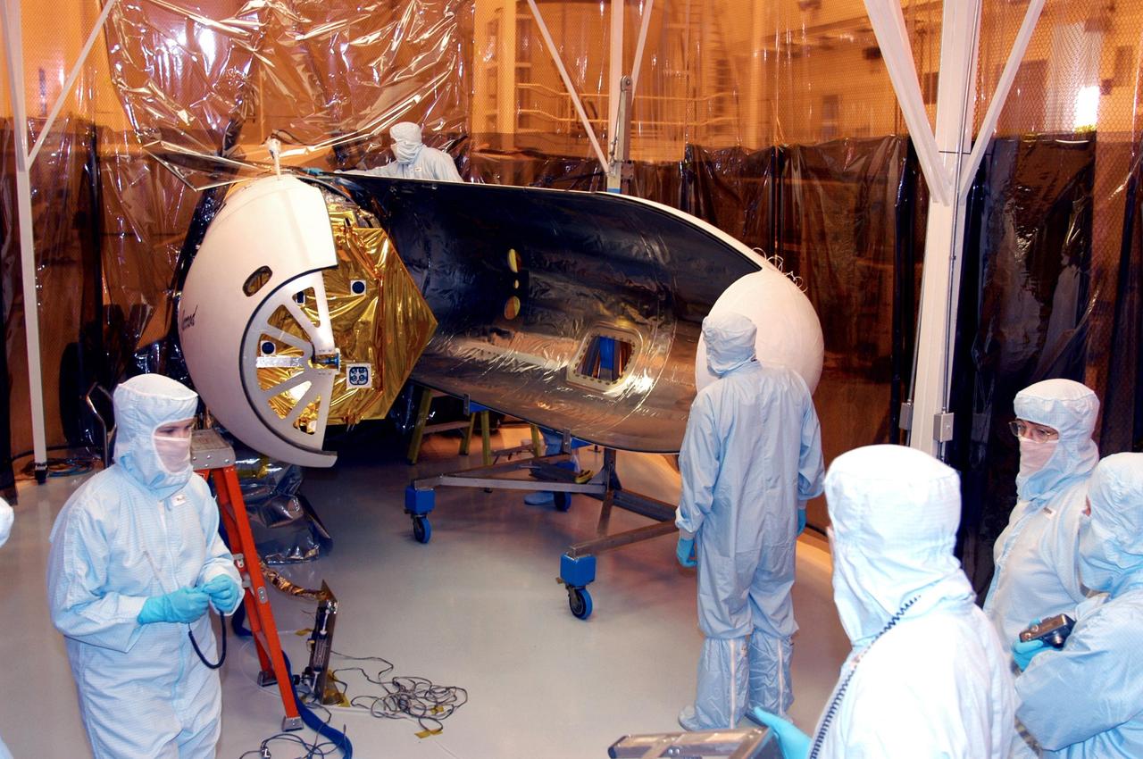 KENNEDY SPACE CENTER, FLA. - The second half of the fairing is moved toward the Solar Radiation and Climate Experiment (SORCE) satellite (left). Built by Orbital Sciences Corporation (OSC), SORCE will study and measure solar irradiance as a source of energy in the Earth's atmosphere.  The launch of SORCE is scheduled for Jan. 25 at 3:14 p.m. from Cape Canaveral Air Force Station, Fla., from a Pegasus XL launch vehicle.  The drop of the Pegasus will be from OSC's L-1011 aircraft at an altitude of 39,000 feet over the Atlantic Ocean approximately 100 miles east-southeast of Cape Canaveral.