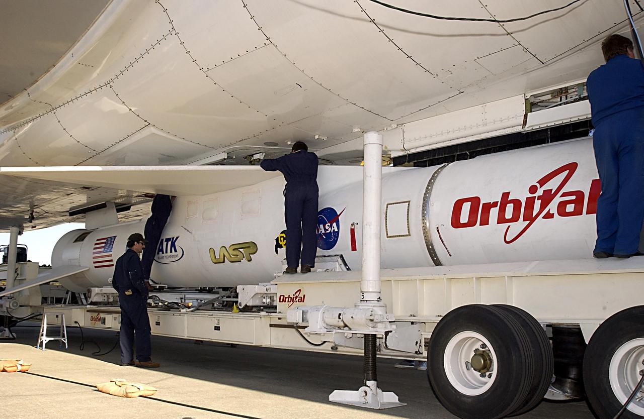 KENNEDY SPACE CENTER, FLA. - Technicians on Cape Canaveral Air Force Station, Fla., work to attach the Pegasus XL launch vehicle and Solar Radiation and Climate Experiment (SORCE) to the L-1011 aircraft. The L-1011 will carry the Pegasus to the launch altitude of 39,000 feet over the Atlantic Ocean approximately 100 miles east-southeast of Cape Canaveral. SORCE, built by Orbital Sciences Corporation, will study and measure solar irradiance as a source of energy in the Earth's atmosphere. The launch of SORCE is scheduled for Jan. 25 at 3:14 p.m. from CCAFS.
